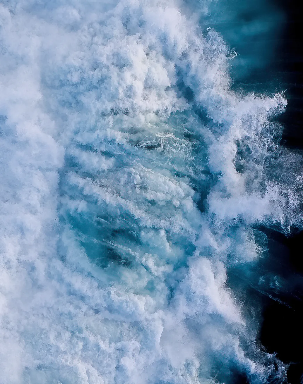 Being caught in a washy chasm of whitewash from a large crashing wave is a disorienting, overwhelming experience. The wave's force slams into you, pulling you under in a chaotic swirl of frothy water, where you're tumbled and twisted, losing all sense of direction. The roar of the wave fills your ears as the powerful current drags you along, making it difficult to regain control or catch your breath. Panic creeps in as your lungs burn for air, but just as the wave's fury begins to subside, you find a moment to surface, gasping for breath in the suddenly calm world above.

Part of the Ocean Air series. A collection of abstract ocean art captured using aerial photography.