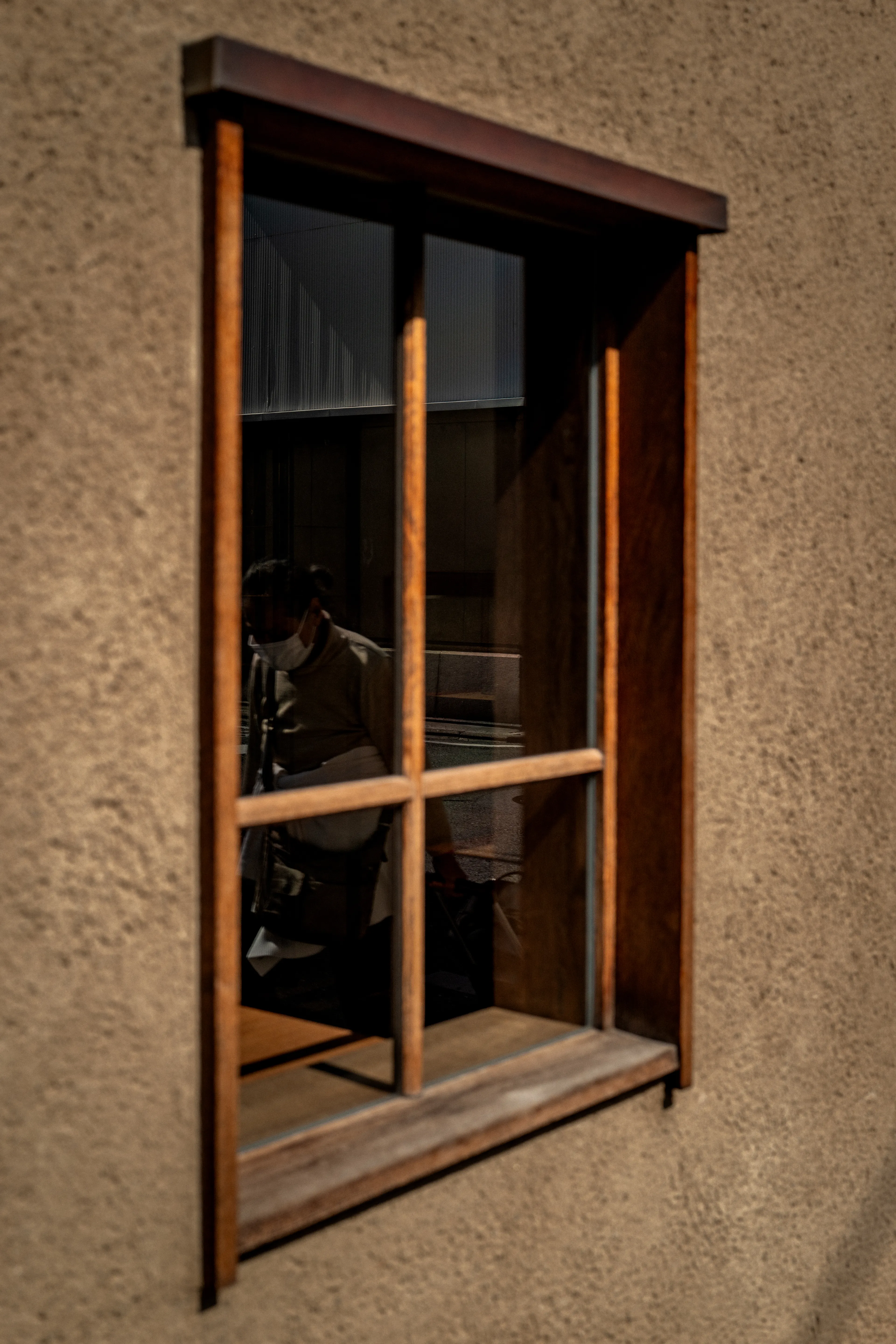 An elderly man walks by, framed in the reflection of a window