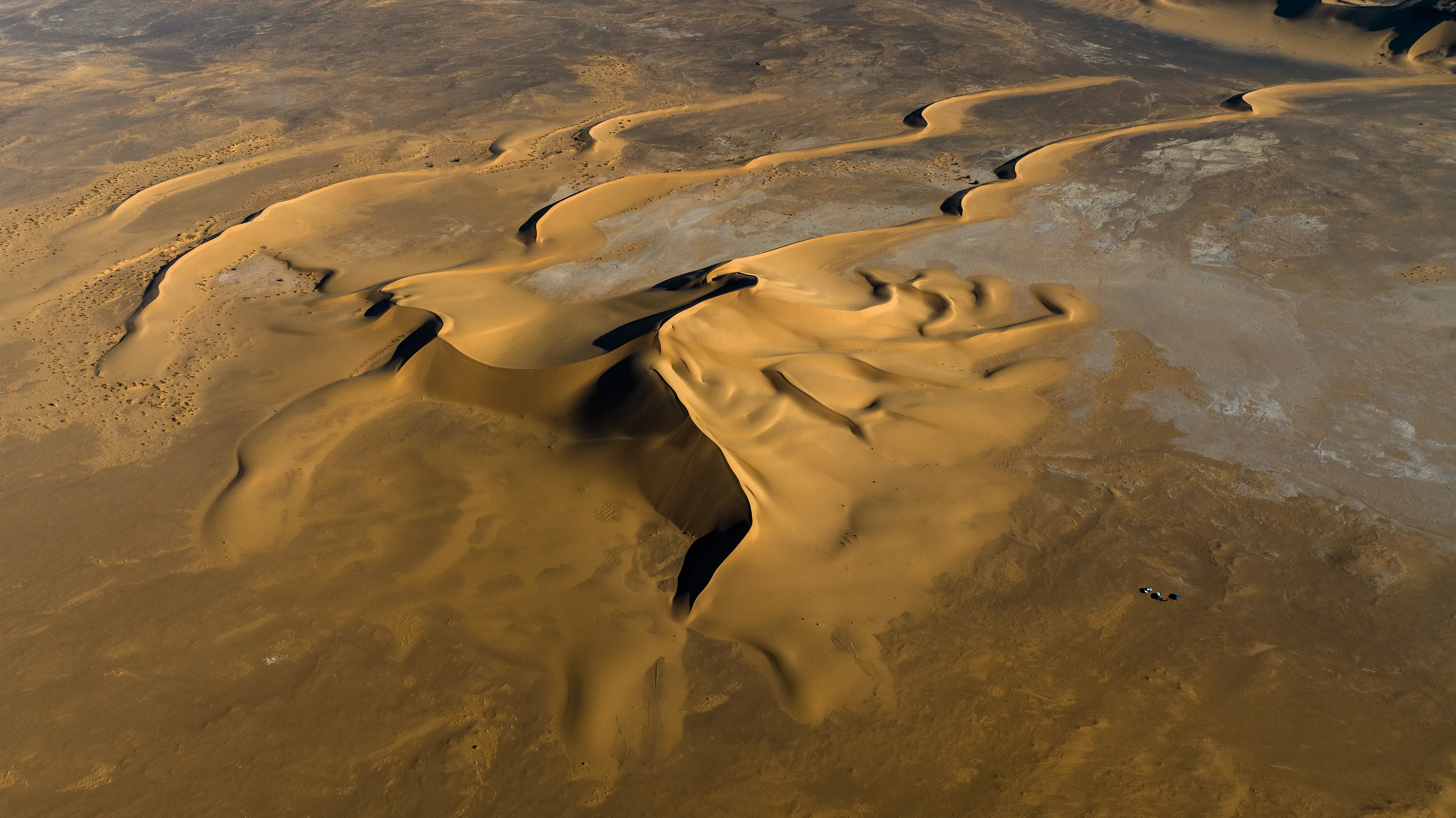 This stunning stretch of sand rises from a dry, flat pan, forming a series of distinctive barchan dunes. We were crossing back through the Sahara from south to north, passing by Magdit along the remote western border between Libya and Algeria, on our way to the ancient caravan town of Ghadames. We found ourselves in the Erg Titersin, a landscape where archaeologists have uncovered stone tumuli and burial structures. As we moved deeper into this immense terrain, we felt incredibly small beside this vast mass of sand dominating the barren desert.