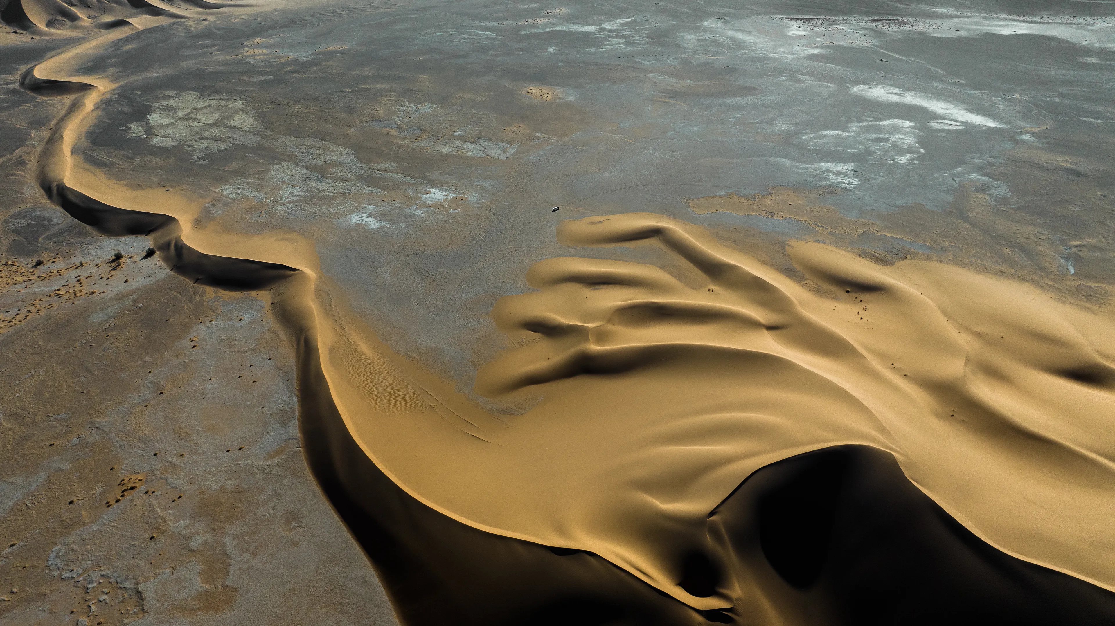 This stunning stretch of sand rises from a dry, flat pan, forming a series of distinctive barchan dunes. We were crossing back through the Sahara from south to north, passing by Magdit along the remote western border between Libya and Algeria, on our way to the ancient caravan town of Ghadames. We found ourselves in the Erg Titersin, a landscape where archaeologists have uncovered stone tumuli and burial structures. As we moved deeper into this immense terrain, we felt incredibly small beside this vast mass of sand dominating the barren desert.