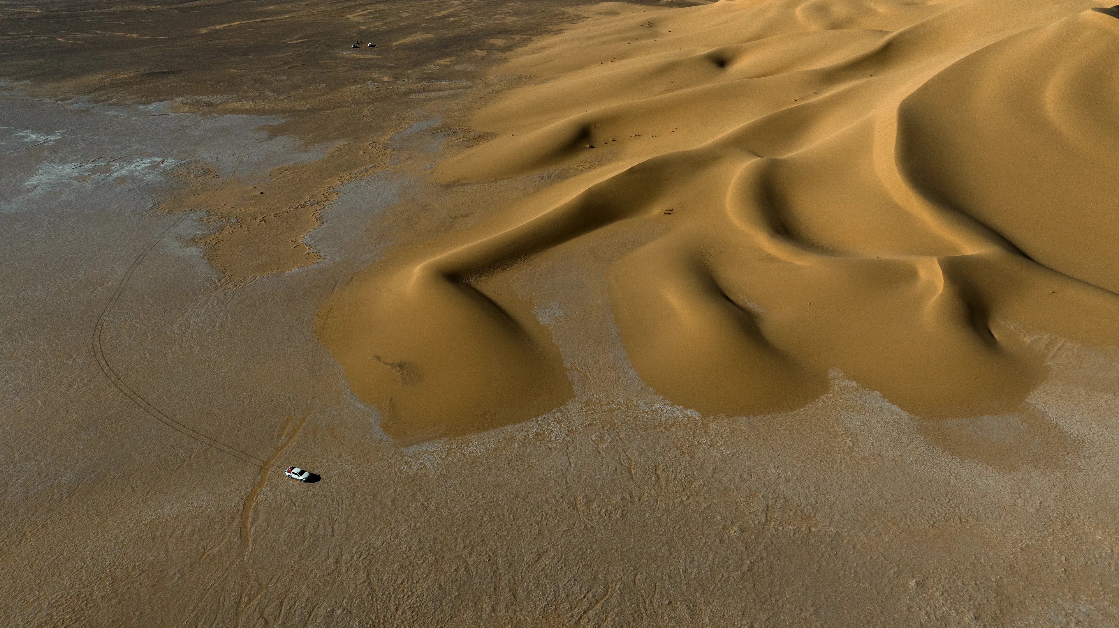 This stunning stretch of sand rises from a dry, flat pan, forming a series of distinctive barchan dunes. We were crossing back through the Sahara from south to north, passing by Magdit along the remote western border between Libya and Algeria, on our way to the ancient caravan town of Ghadames. We found ourselves in the Erg Titersin, a landscape where archaeologists have uncovered stone tumuli and burial structures. As we moved deeper into this immense terrain, we felt incredibly small beside this vast mass of sand dominating the barren desert.