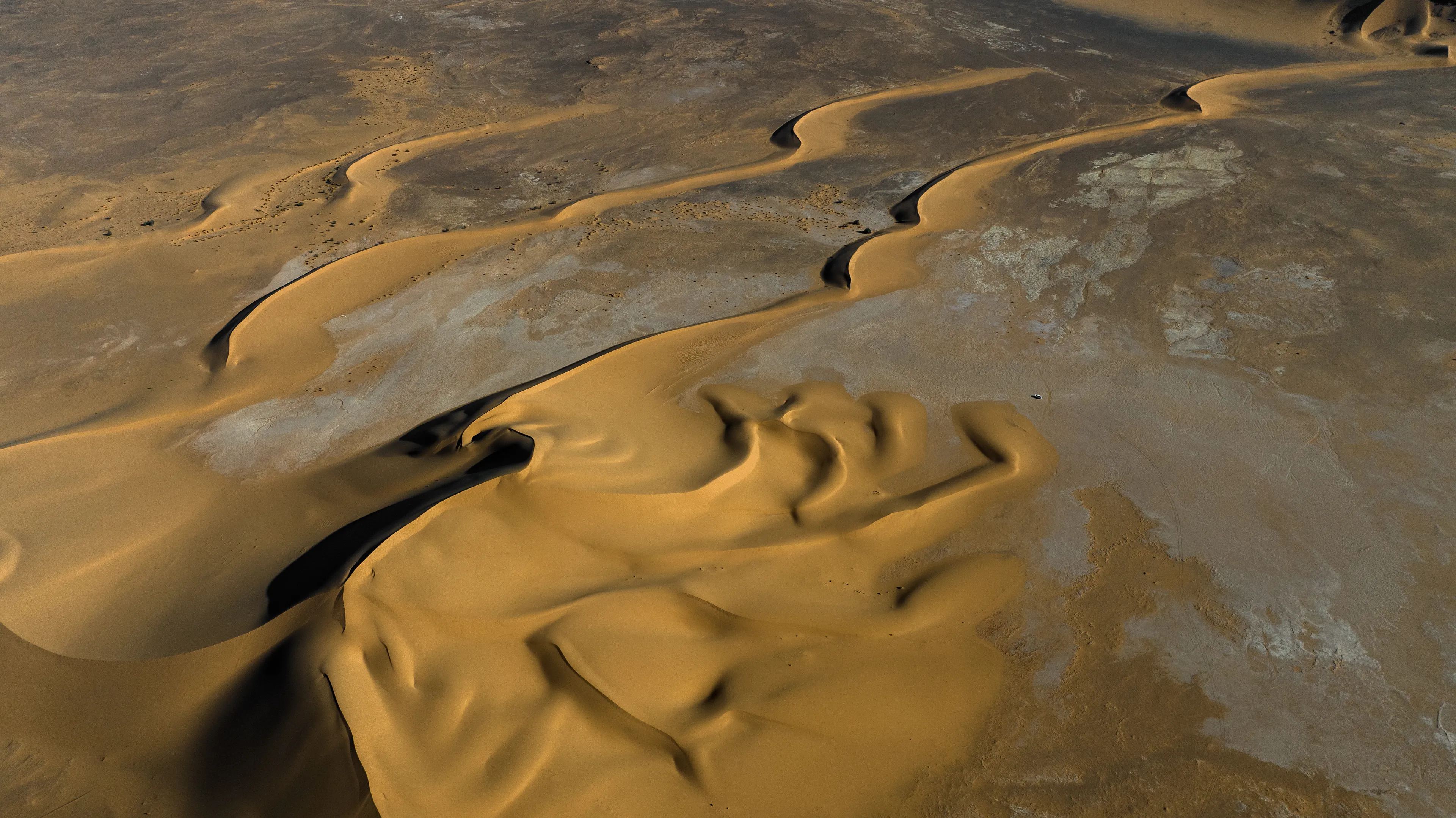 This stunning stretch of sand rises from a dry, flat pan, forming a series of distinctive barchan dunes. We were crossing back through the Sahara from south to north, passing by Magdit along the remote western border between Libya and Algeria, on our way to the ancient caravan town of Ghadames. We found ourselves in the Erg Titersin, a landscape where archaeologists have uncovered stone tumuli and burial structures. As we moved deeper into this immense terrain, we felt incredibly small beside this vast mass of sand dominating the barren desert.