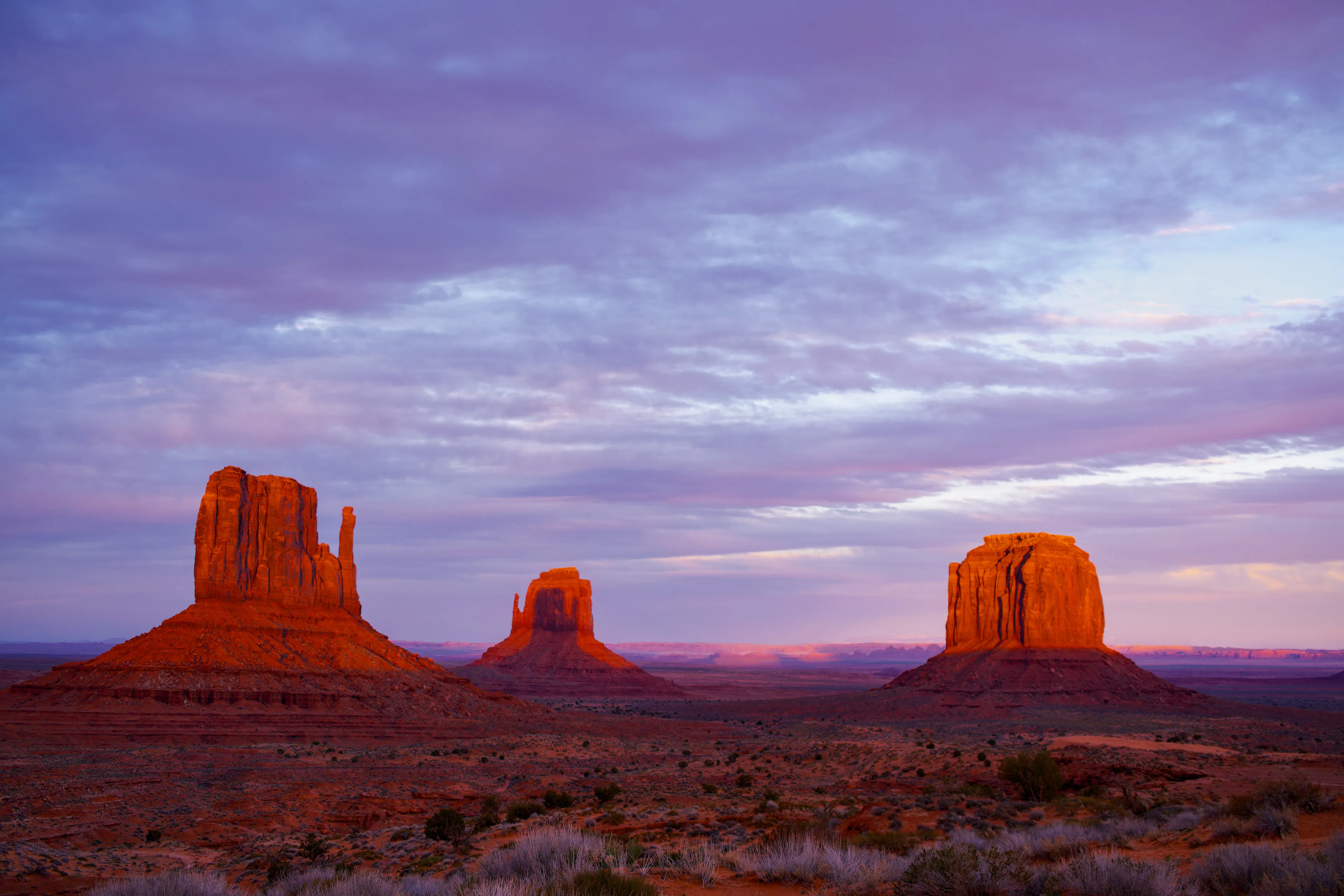 This photograph captures a truly unique phenomenon in the heart of Monument Valley, a majestic landscape known for its iconic mesas and stunning rock formations. This single image showcases three towering mesas, each casting their long shadows in the warm glow of the setting sun. In a remarkable coincidence, the shadow of one mesa appears to perfectly align with the other, creating the illusion of a "high five" between the two geological wonders.

The contrast between the rich red hues of the mesas and the dark shadows creates a striking visual effect, highlighting the dramatic play of light and shadow that defines the beauty of Monument Valley. The image invites viewers to marvel at the wonders of nature, as the mesas seemingly reach out to each other in a moment of camaraderie and celebration.

This photograph was taken by awhurst.

Edition 1/1