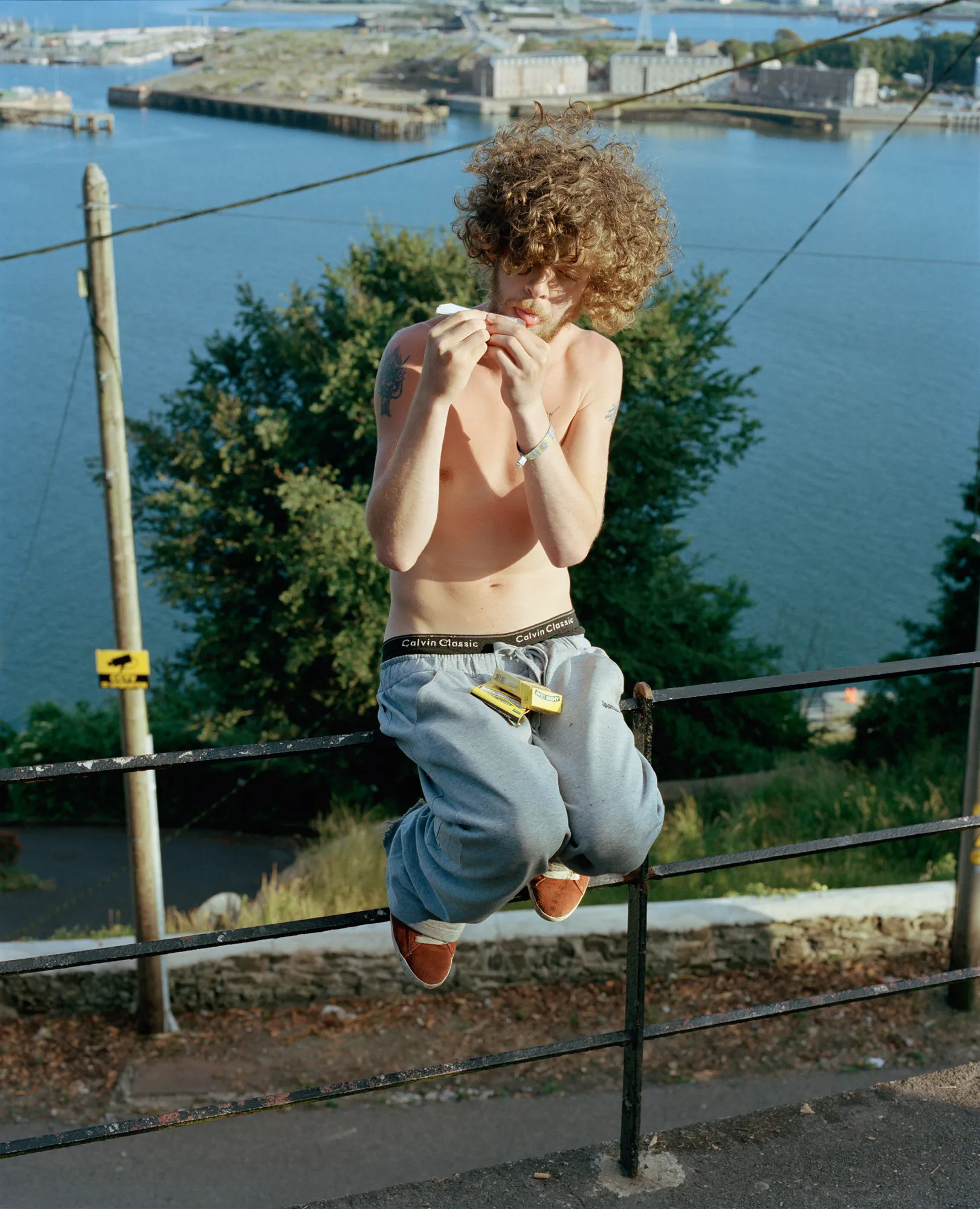 Image caption: Adam on the black rails overlooking Haulbowline Island, headquarters for the Irish Naval Service.

Assembly and Sasha Wolf Projects present “My Last Day at Seventeen,” the genesis NFT collection by an American photographer Doug DuBois. Combining portraits, spontaneous encounters and collaborative performances, the images in "My Last Day at Seventeen" hover between documentary and fiction. Doug DuBois was first introduced to a group of teenagers from the Russell Heights housing estate while he was an artist-in-residence in Cobh, on the southwest coast of Ireland. He was fascinated by the insular neighborhood, in which "everyone seems to be someone's cousin, former girlfriend, or spouse." DuBois gained entry when two participants of a workshop he taught took him to a local hangout spot, opening his eyes to a world of not-quite-adults, struggling through the last days of their childhood. Over the course of five years, DuBois returned to Russell Heights examining the uncertainties of growing up in Ireland today while highlighting the unique relationship between artist and subject.

Doug Dubois is a widely-exhibited American photographer well known for capturing intimate familial scenes. His photographs are in the collection of the Museum of Modern Art in NY; SFMOMA in San Francisco; J. Paul Getty Museum and LACMA in Los Angeles; The Museum of Fine Art in Houston; the Library of Congress in Washington DC; and the Victoria and Albert Museum, London.