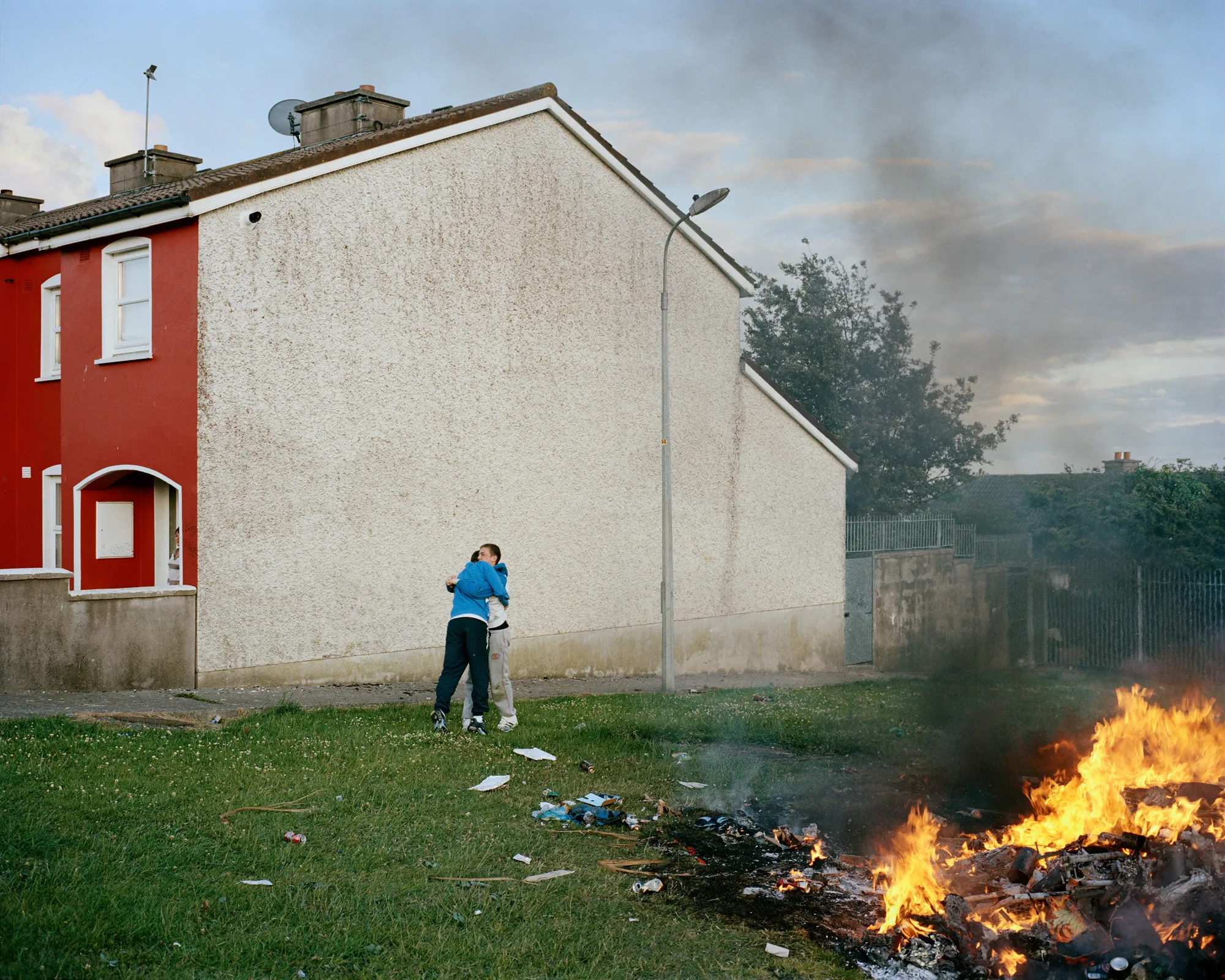 Image caption: The fire brigade comes each year to extinguish the bonfire. Just as soon as they leave, the kids light it up again. The embers will burn well into the evening—neighbors will set up chairs, drink a bit too much, argue, laugh and make up.

Assembly and Sasha Wolf Projects present “My Last Day at Seventeen,” the genesis NFT collection by an American photographer Doug DuBois. Combining portraits, spontaneous encounters and collaborative performances, the images in "My Last Day at Seventeen" hover between documentary and fiction. Doug DuBois was first introduced to a group of teenagers from the Russell Heights housing estate while he was an artist-in-residence in Cobh, on the southwest coast of Ireland. He was fascinated by the insular neighborhood, in which "everyone seems to be someone's cousin, former girlfriend, or spouse." DuBois gained entry when two participants of a workshop he taught took him to a local hangout spot, opening his eyes to a world of not-quite-adults, struggling through the last days of their childhood. Over the course of five years, DuBois returned to Russell Heights examining the uncertainties of growing up in Ireland today while highlighting the unique relationship between artist and subject.

Doug Dubois is a widely-exhibited American photographer well known for capturing intimate familial scenes. His photographs are in the collection of the Museum of Modern Art in NY; SFMOMA in San Francisco; J. Paul Getty Museum and LACMA in Los Angeles; The Museum of Fine Art in Houston; the Library of Congress in Washington DC; and the Victoria and Albert Museum, London.