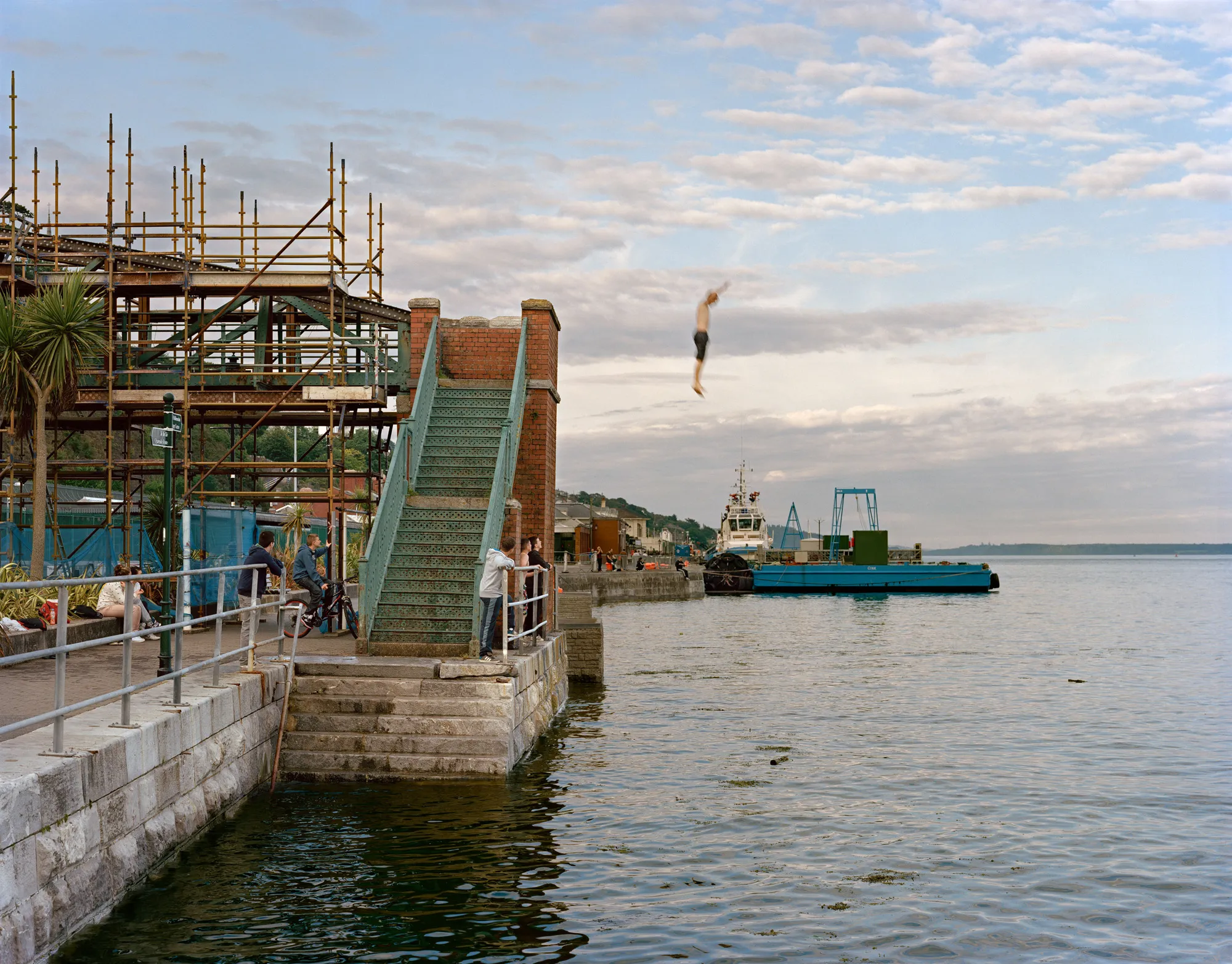 Image caption: Sweeny jumped into Cork Harbor on my count of three on a summer evening in 2012. He was fourteen, enacting a ritual that went back generations and required the courage and faith that no matter how deep the water, you can always reach the shore.

Assembly and Sasha Wolf Projects present “My Last Day at Seventeen,” the genesis NFT collection by an American photographer Doug DuBois. Combining portraits, spontaneous encounters and collaborative performances, the images in "My Last Day at Seventeen" hover between documentary and fiction. Doug DuBois was first introduced to a group of teenagers from the Russell Heights housing estate while he was an artist-in-residence in Cobh, on the southwest coast of Ireland. He was fascinated by the insular neighborhood, in which "everyone seems to be someone's cousin, former girlfriend, or spouse." DuBois gained entry when two participants of a workshop he taught took him to a local hangout spot, opening his eyes to a world of not-quite-adults, struggling through the last days of their childhood. Over the course of five years, DuBois returned to Russell Heights examining the uncertainties of growing up in Ireland today while highlighting the unique relationship between artist and subject.

Doug Dubois is a widely-exhibited American photographer well known for capturing intimate familial scenes. His photographs are in the collection of the Museum of Modern Art in NY; SFMOMA in San Francisco; J. Paul Getty Museum and LACMA in Los Angeles; The Museum of Fine Art in Houston; the Library of Congress in Washington DC; and the Victoria and Albert Museum, London.