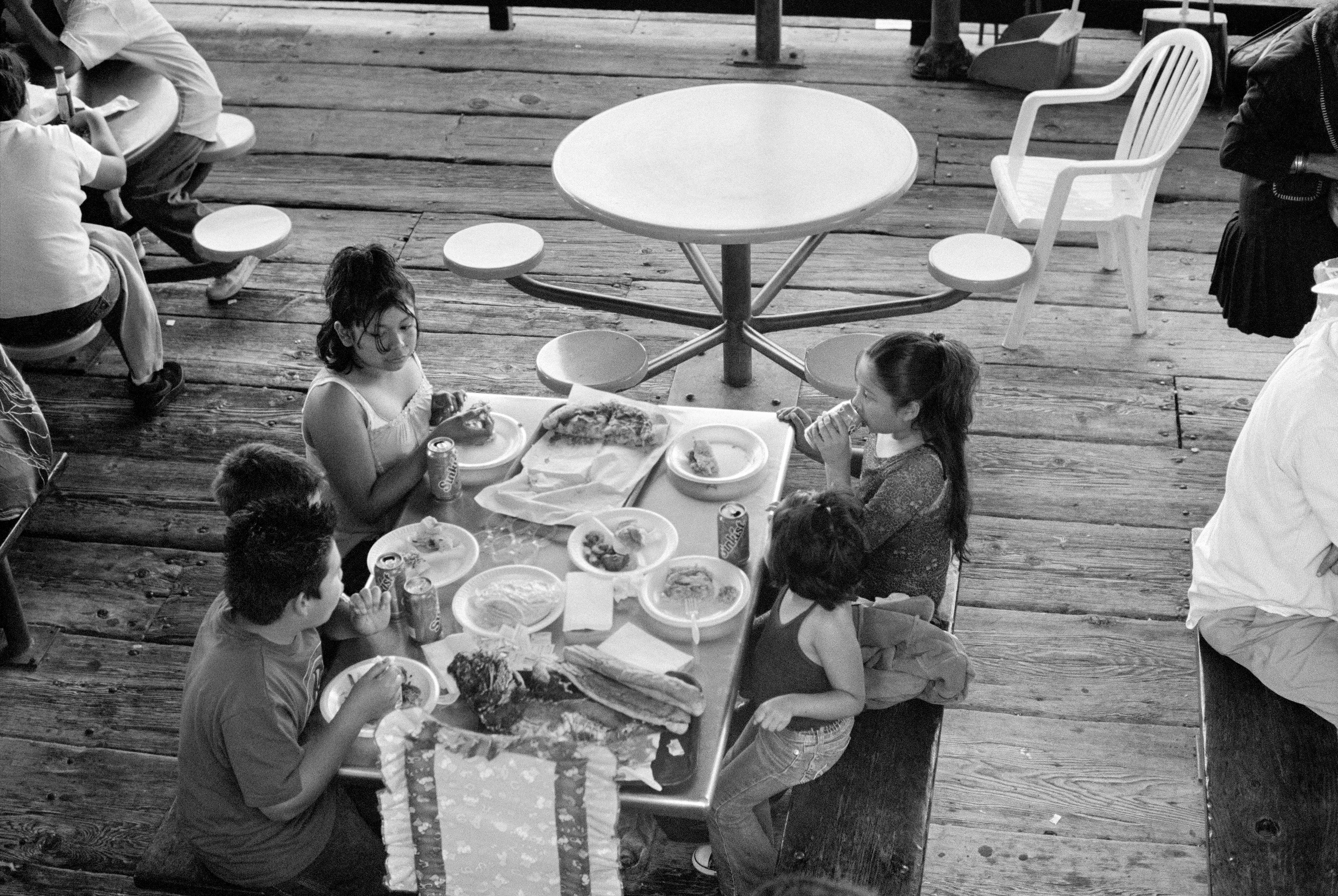 THE VILLAGE #10 KIDS EATING AND DRINKING SUNKIST by Deanna Templeton

This project started in 2002. A year after my mother passed away, a few years after my father passed. What I remember was one day I was thinking about my parents and feeling a little bit lonely, a little empty and decided to go for a drive. So I decided to drive out to my grandmother's house in San Pedro, which is about a 45 minute drive from where I live. I just wanted to reminisce, to re-explore the surroundings where I would go when I was a child. The liquor store I would walk to to get a Lipton Ice Tea and a bag of Frito’s, to the bakery where I swore all the cookies didn’t have sugar in them and then I drove over to Ports O’Call Village. As soon as I started to walk around I came across a stage with some Mariachis playing and it just hit me, I felt like I was home, I was with family. Over the next 5 years, whenever I could, I started going out there on the weekends. Getting reacquainted with the village and the locals. To shoot everything I wanted to remember.

Edition: 1 of 1

Commissioned by Obscura