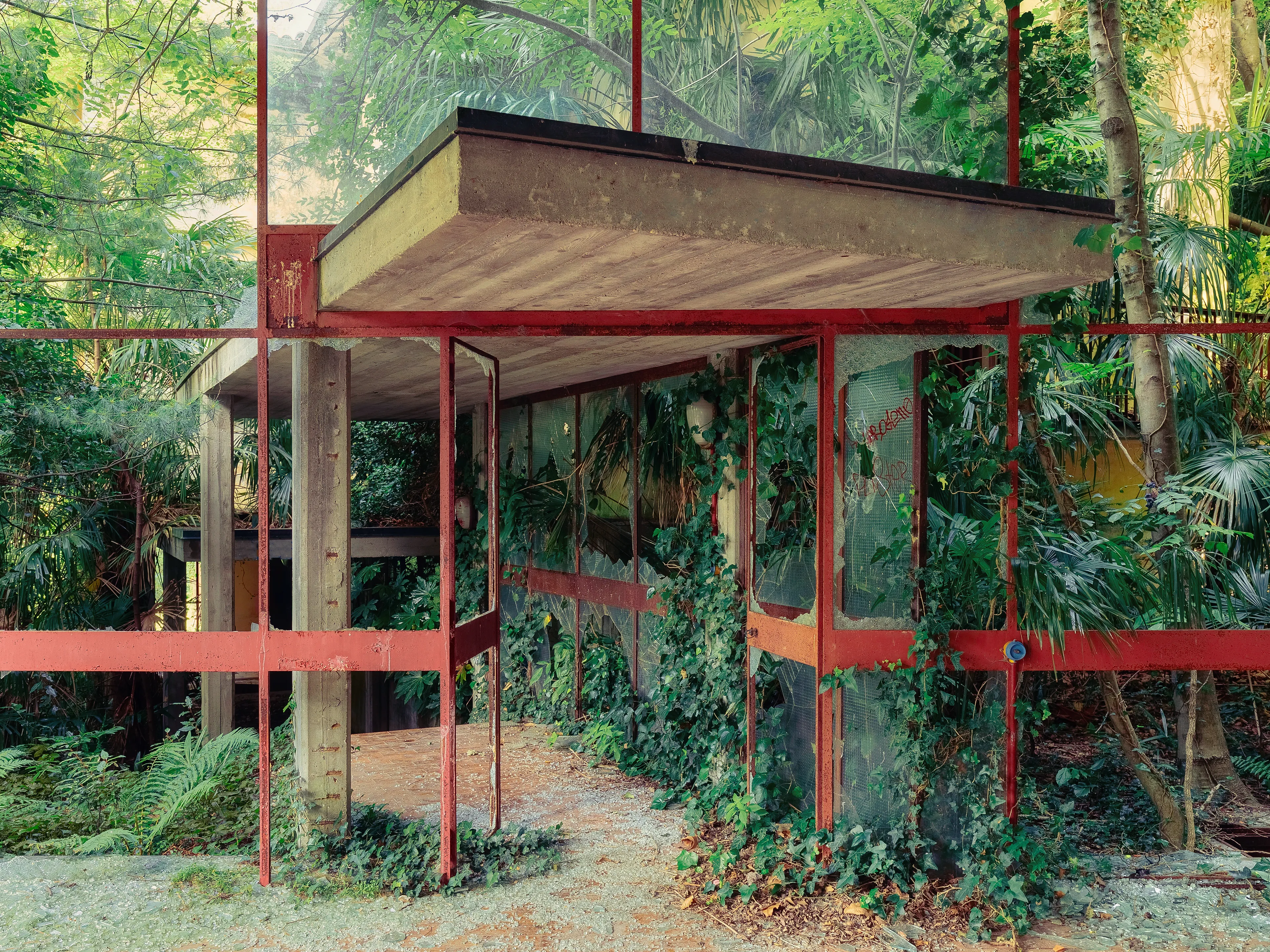 This holiday camp for children is located high in the mountains above a large lake. 

The huge complex disappears more and more in a jungle of palm trees and wild plants where by a completely new flair has formed here. The exit of the huge dining room now looks like a gateway to another world.