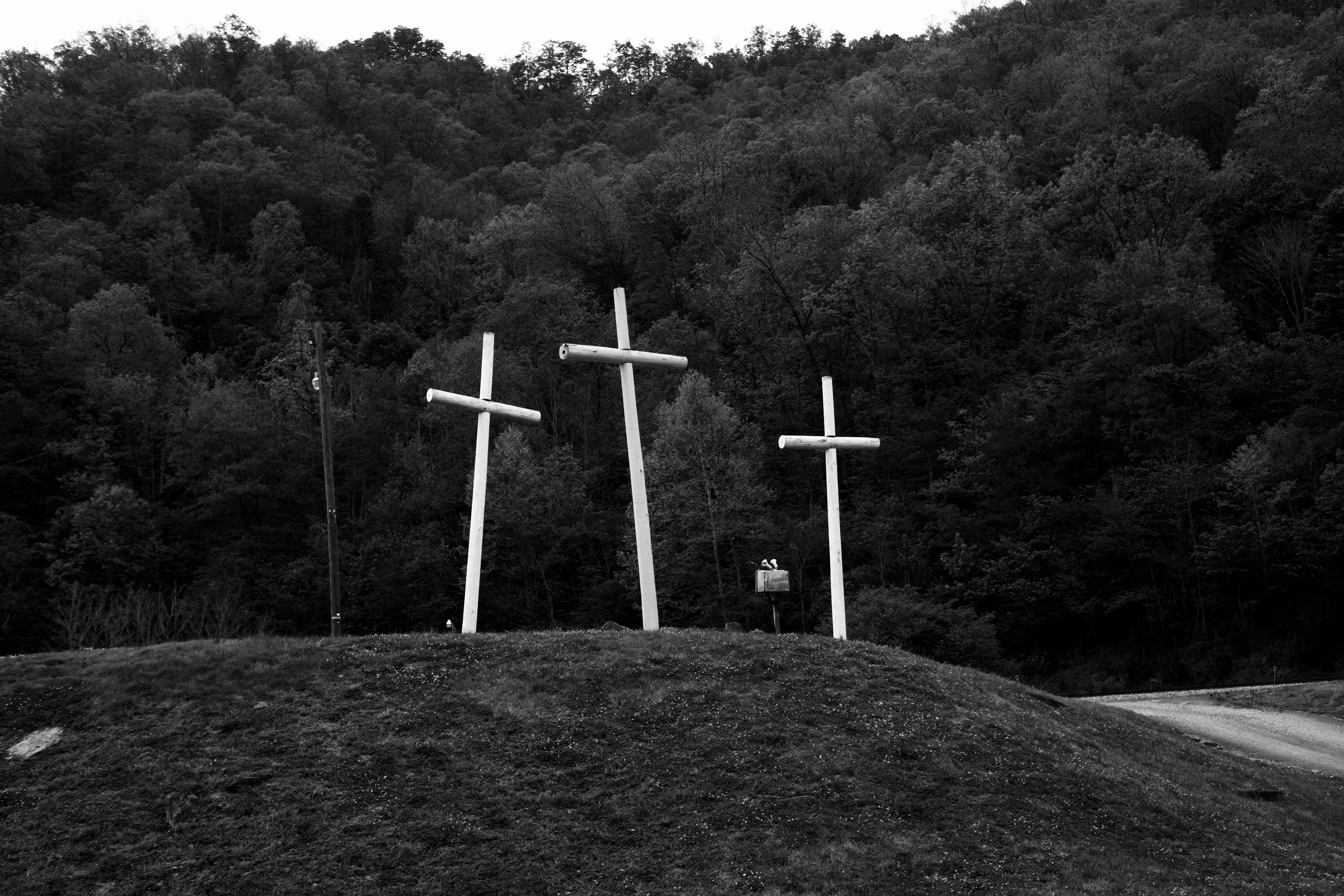 West Virginia and the Appalachian Mountains have an allure about them that is almost impossible to ignore. The country is rugged and so are the individuals who inhabit these mountains. As you ascend into the deep mountain of Appalachia, the roads begin to wind almost unimaginably. As you drive, sharp left and right turns seem to never end as Empress trees and Black Pines hug the roads like guardians of a passageway. Large metal structures from coal mines stand like old ruins. As you continue to drive deeper and deeper within the mountains small towns start to pop up, not more than 1/2 mile in length alongside Route 16. For every ten homes there seems to be a church, affirming that the presence of religion is strong and deeply rooted in these mountains.

A small church by the name "The House of The Lord Jesus" sits on the side of the road in the quiet and humble town of Squire, with a population of fewer than 300 people. If you didn't know any better, you'd think it's just like all the other churches you pass by while driving up the windy mountain roads. This Holiness church practices what is called "signs following." The church is small and is run by pastor Chris Wolford. Twelve church pews (six on each side) take up the majority of the space. Old wood panels cover the walls and red burgundy carpet melds with a wood floor at the front of the church. As you walk down the center of the church you see women laying on their knees bent over the pews praying and crying before the service begins. The sound of rattlesnake rattlers fill the air and multiple boxes are laid out behind the pulpit, while the guitar begins to blair over the speakers at full volume. The music is incredible...with a mix of delta blues and bluegrass, it's a style of its own and specific to this type of worship within the applications. Women are spinning in their flowing dresses and their long hair is wrapped up in cloths. Chris grabs a mason jar. Within it is a mixture of water and strychnine poison. Small dixie cups line the front of the pulpit as he fills one and takes a shot. A bottle is brought out, stuffed with alcohol and homemade wick. He lights the top and flames rise above the glass bottle. He screams passionately in praises as he holds the bottle underneath his chin. He eventually passes the lit bottle to his mother as she also holds it under her chin and begins to spin in circles. Chris jumps and dances in a stomping manner and praises the Lord as beads of sweat and tears stream down his head and face. He reaches and grabs one of the wooden boxes from behind him, and flips open the plexiglass lid. He pulls out a diamondback rattlesnake and holds it straight into the air. He jumps around, dances, and screams in praise as the serpent rests in his hand and looks over the church. The energy is so palpable it makes the hair on the back of your neck stand up and the feeling is almost unexplainable.

There is death in this, as well as a lot of suffering for the church and this whole region of West Virginia. But I came to understand why the Appalachians have this mystic quality. They're full of love and compassion...you just have to sift through all the coal dust to find it.

Welcome to GLORYLAND.

A grant provided by Fellowship Futures supported this image and the minting of the GLORYLAND collection.