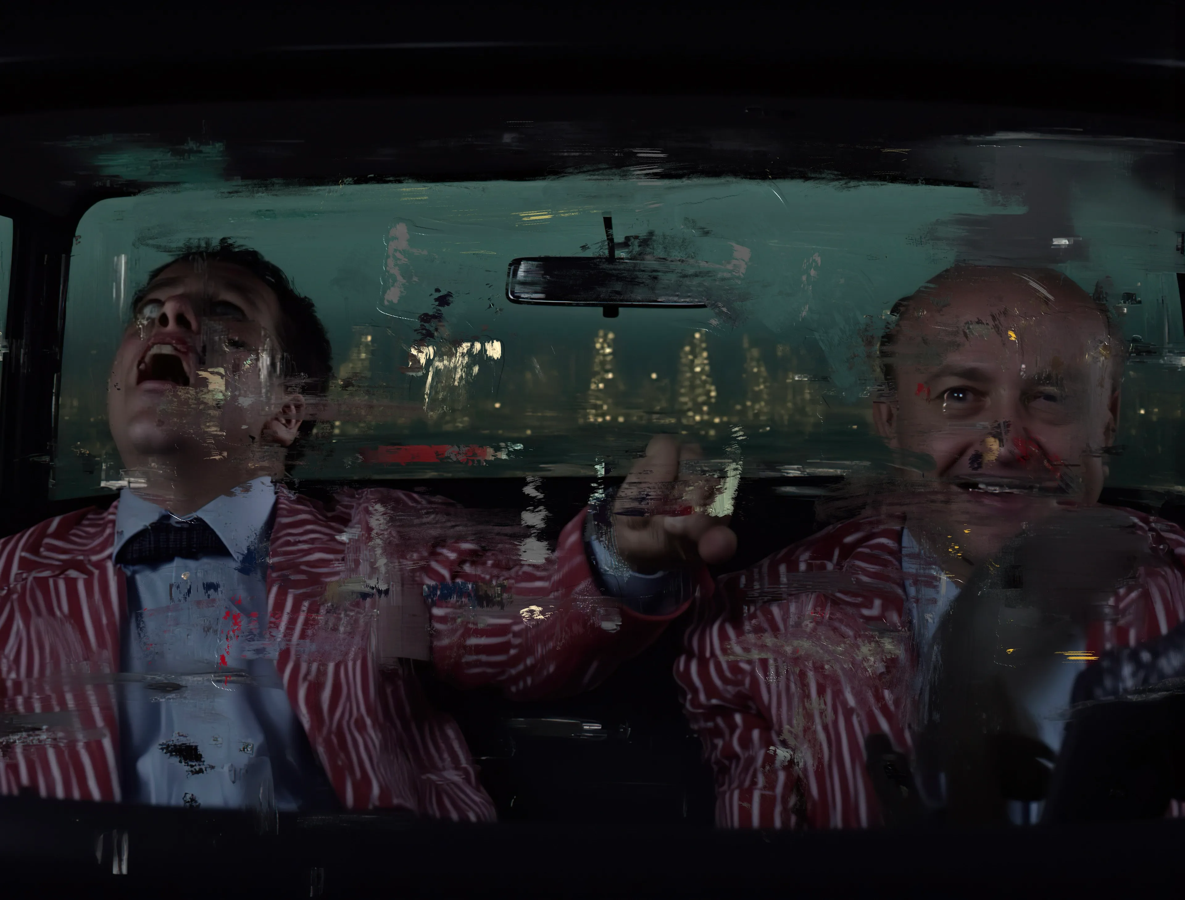 They sit like kings in a kingdom of ruin,
Suits red as arterial dreams,
Laughter spilling out like blood from a wound—
Wet, relentless, unearned.

The road has given up,
A gray smear of nothingness.
Streetlights flicker, half-dead witnesses,
Casting halos on cracked glass and striped fabric,
While the world outside chokes on its silence.

Their eyes—
One wild with electric frenzy,
The other carved from dark mirth—
Burn through the windshield,
Begging the universe to blink first.

Is it a victory or a joke?
Does it matter?

The night stretches out ahead,
Long as a confession they'll never make,
And in their laughter, you hear it—
The sound of something coming undone,
Not all at once,
But slowly, beautifully, like velvet pulling apart at the seams.