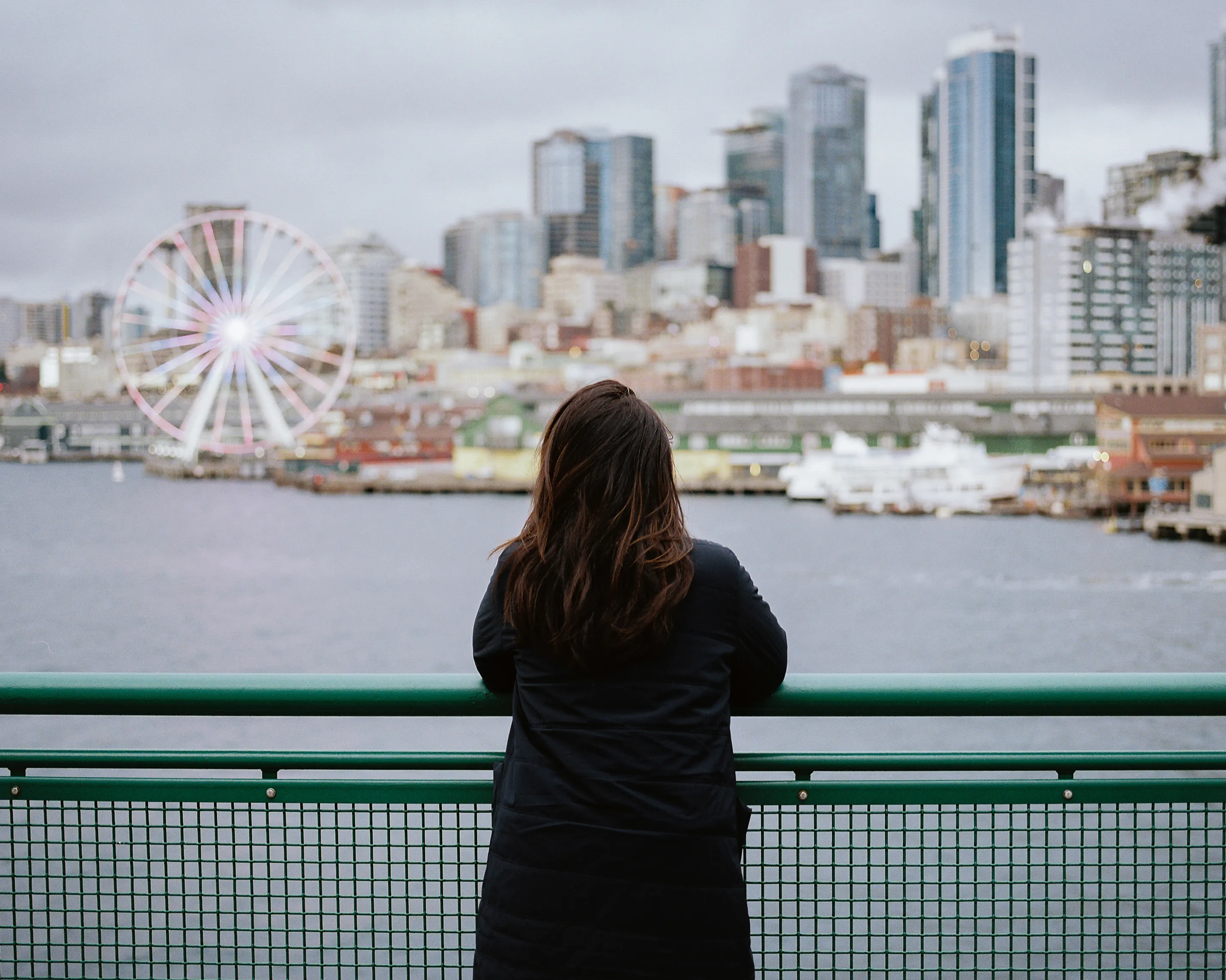 A passenger takes in the distant view of the Seattle skyline as the ferry departs.