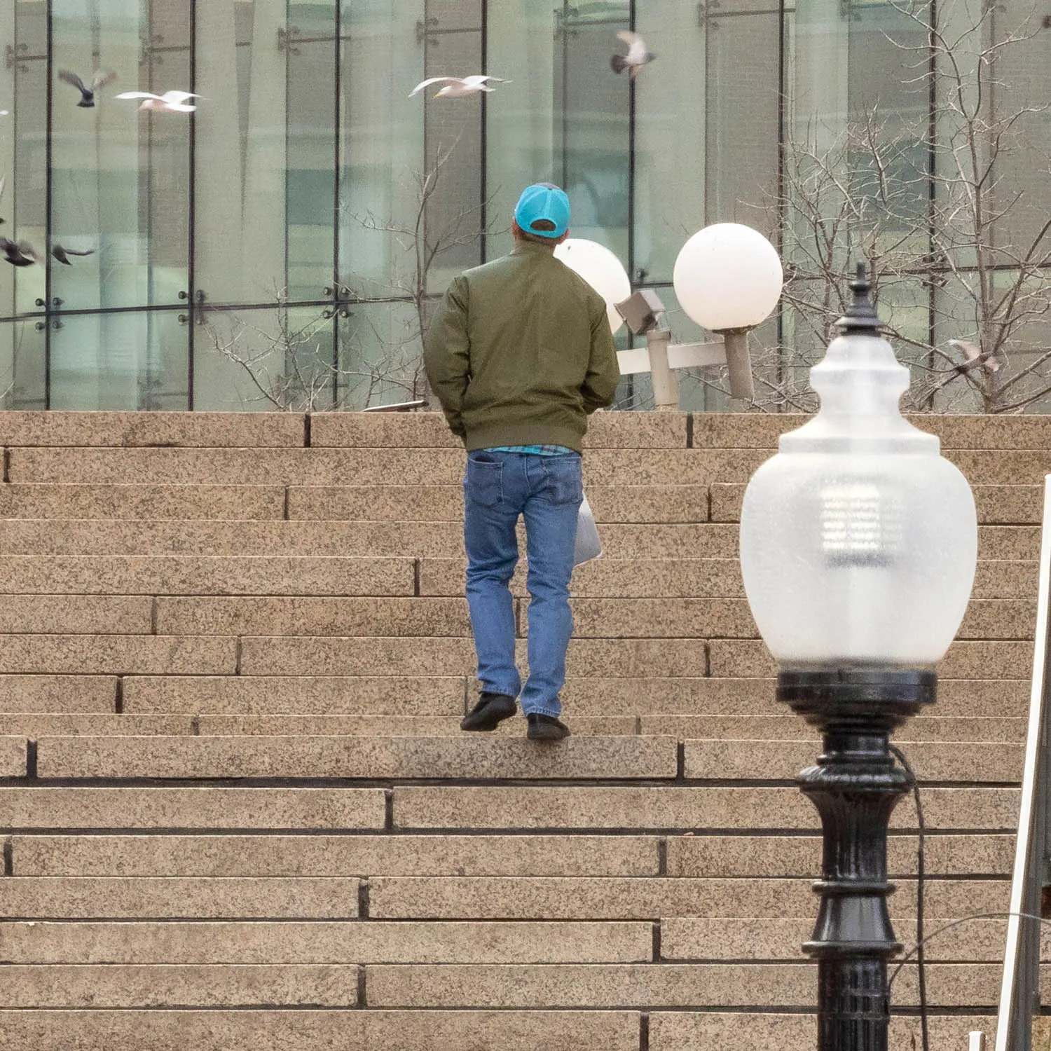 About an Hour: Down and Up (Government Center Steps, Boston, 3,120 exposures from 3:11 to 4:13 pm, March 20, 2022)

About an Hour is a series of photographs of a large staircase at Government Center, Boston. The project consists of two composite photos and 123 pendants derived from the main photo.  One main photo shows only people going down the stairs and facing the camera. The other main photo shows only people going up the stairs with their backs to the camera. The pendants show each figure in isolation, and they are named by the moment I tripped the shutter. The main composites make a generalization. The pendants show the particular.

Each figure in the photos remains in its real, original place. I change nothing. I simply decide what to keep in and what to leave out. The result is both a true record of an hour and an interpretation of it. The camera simply records what’s in front of it, and the moments couldn’t be more ordinary. But to my way of thinking, no one moment is ever typical or repeatable. Each moment holds a mystery, some poetry, some comedy--and lots of tragedy because it is gone as soon as it arrives. The camera can’t arrest the tragedy, of course, but it preserves the mystery.
