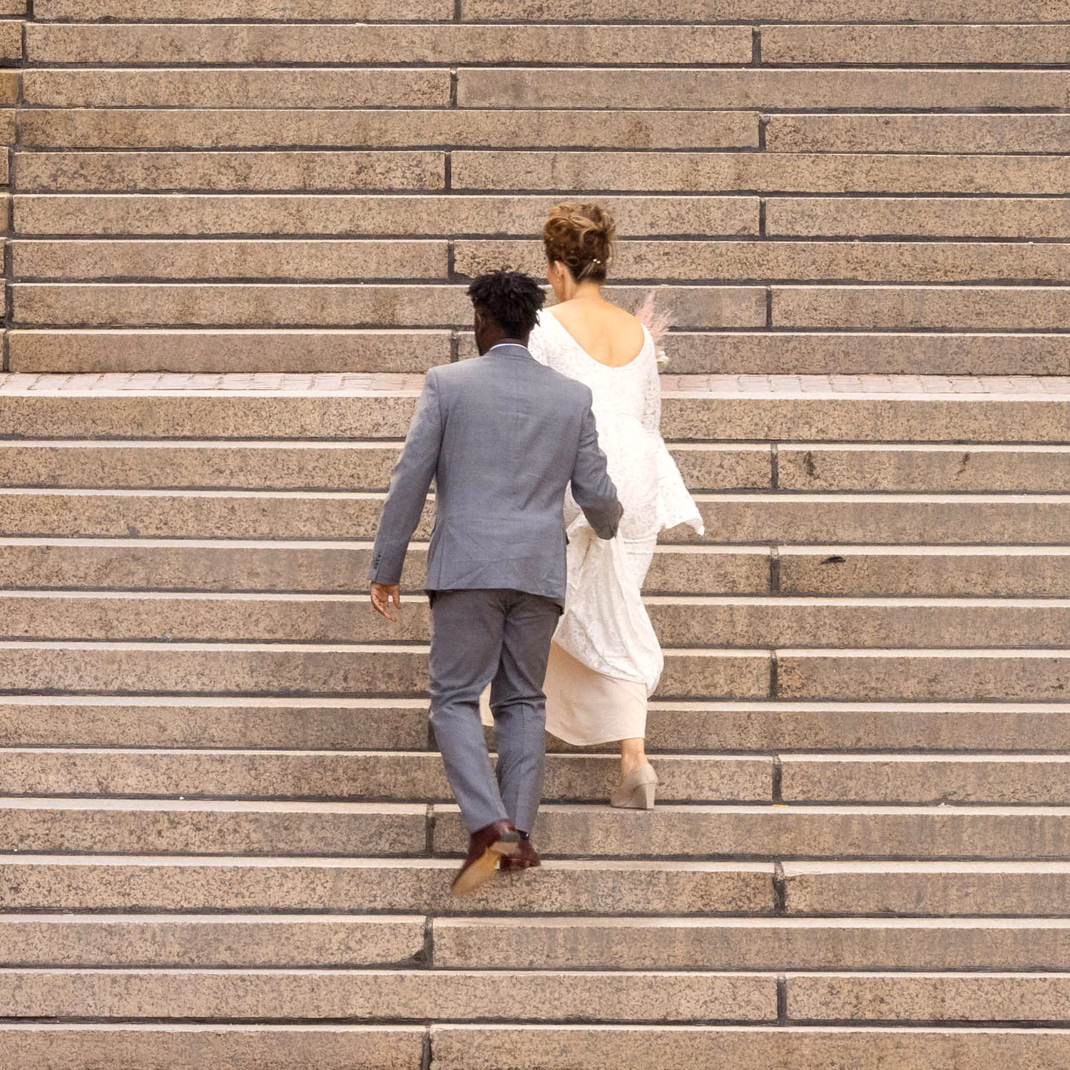 About an Hour: Down and Up (Government Center Steps, Boston, 3,120 exposures from 3:11 to 4:13 pm, March 20, 2022)

About an Hour is a series of photographs of a large staircase at Government Center, Boston. The project consists of two composite photos and 123 pendants derived from the main photo.  One main photo shows only people going down the stairs and facing the camera. The other main photo shows only people going up the stairs with their backs to the camera. The pendants show each figure in isolation, and they are named by the moment I tripped the shutter. The main composites make a generalization. The pendants show the particular.

Each figure in the photos remains in its real, original place. I change nothing. I simply decide what to keep in and what to leave out. The result is both a true record of an hour and an interpretation of it. The camera simply records what’s in front of it, and the moments couldn’t be more ordinary. But to my way of thinking, no one moment is ever typical or repeatable. Each moment holds a mystery, some poetry, some comedy--and lots of tragedy because it is gone as soon as it arrives. The camera can’t arrest the tragedy, of course, but it preserves the mystery.
