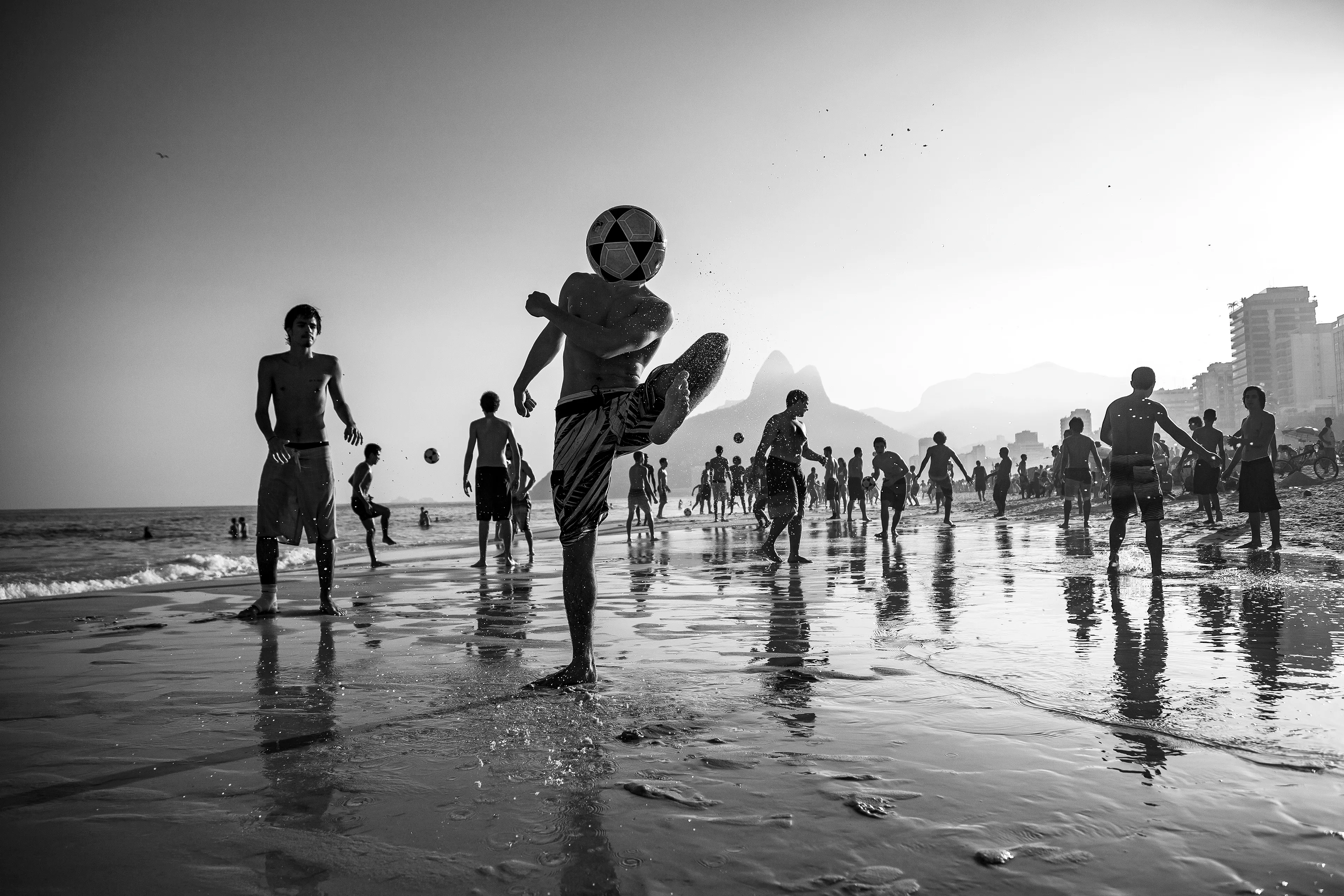 This photograph is part of my Rio de Janeiro series.
I moved to the city and for a year I walked 10 kilometers every day along the beaches looking for scenes that represented Rio de Janeiro and the cariocas.
I was enchanted by the game altinha (cultural heritage), by the soccer ball, by the intense energy, where everything seemed to be magical, where there is no social and cultural separation. No kind of difference between people, one of the most democratic and free places you can be.
I tried to make the photograph seem to have movement as if it were a ballet and in the background, a wonderful setting, a perfect light reflecting on the silhouette of the city, the hills and the sea.

Brazil, Rio de Janeiro, 2015
3937 × 2625 pixels