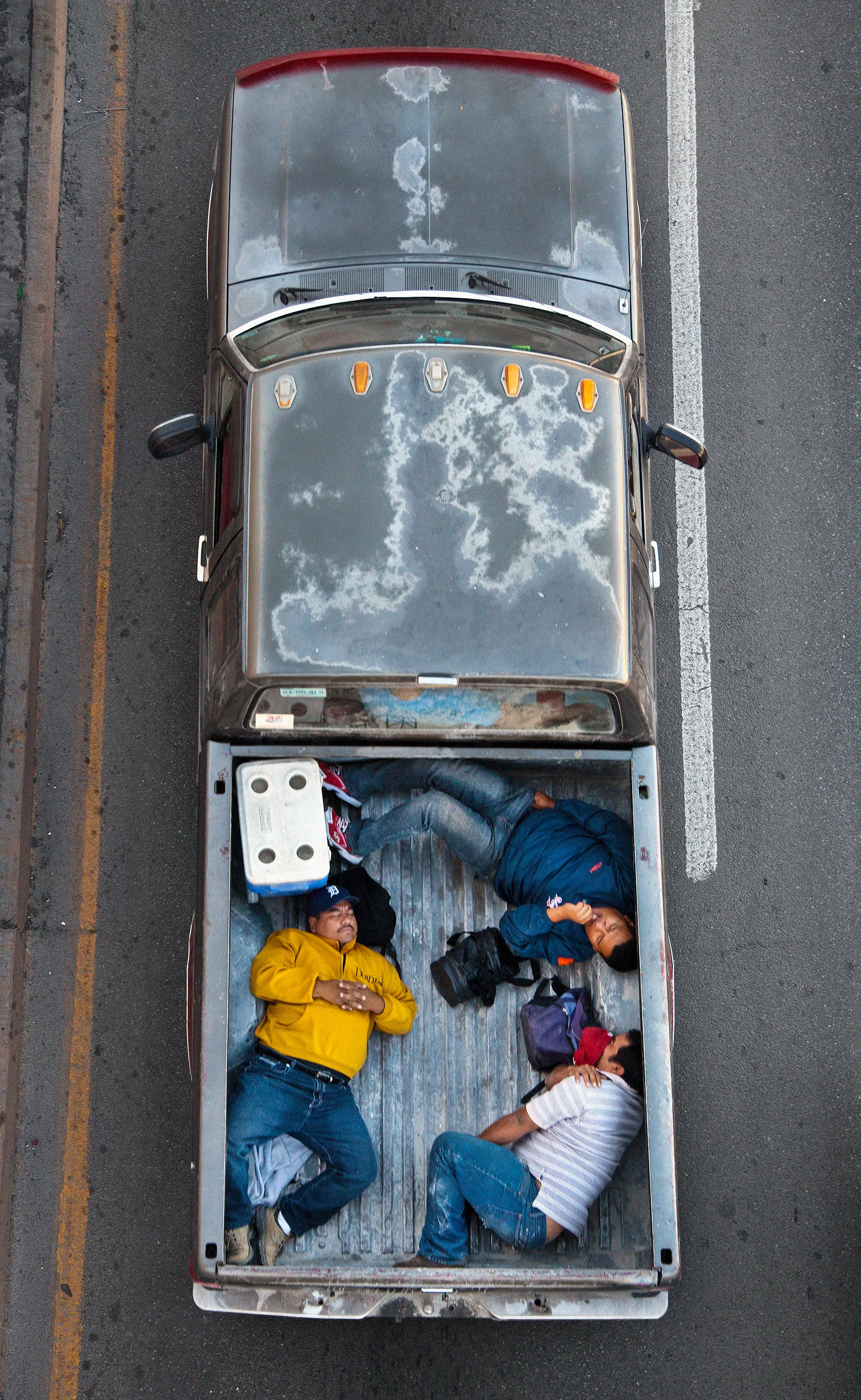 This photograph is part of my series, Carpoolers, which depicts laborers in México captured from an overpass, commuting between distant suburbs and urban centers. Like much of my work, this project comes from a desire to tell the story of the dramatic environmental, economic, and demographic changes playing out in my home city of Monterrey. This series has circulated the internet since 2011 and has been exhibited widely around the world. This piece is part of a collection of 50 works.