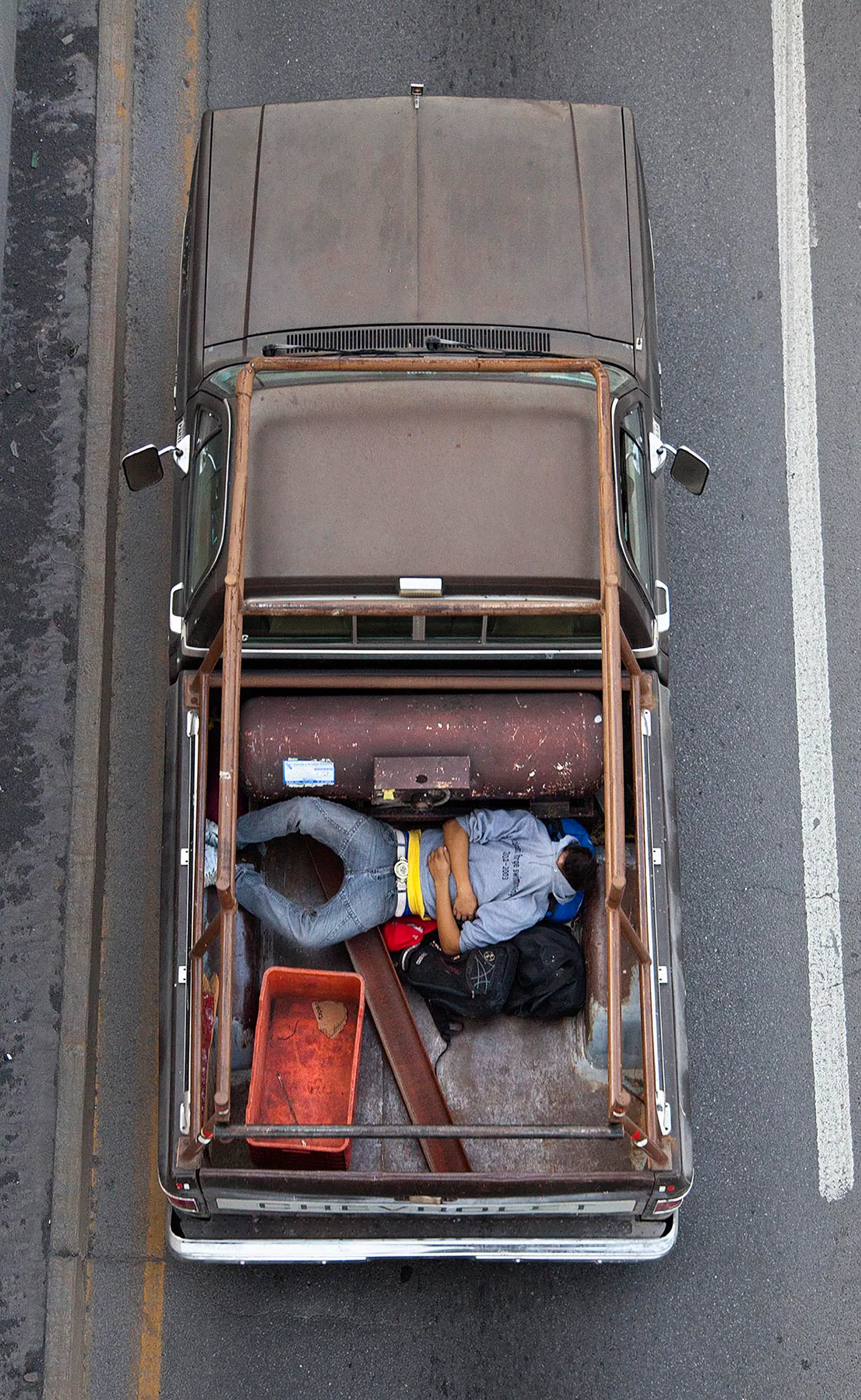 This photograph is part of my series, Carpoolers, which depicts laborers in México captured from an overpass, commuting between distant suburbs and urban centers. Like much of my work, this project comes from a desire to tell the story of the dramatic environmental, economic, and demographic changes playing out in my home city of Monterrey. This series has circulated the internet since 2011 and has been exhibited widely around the world.