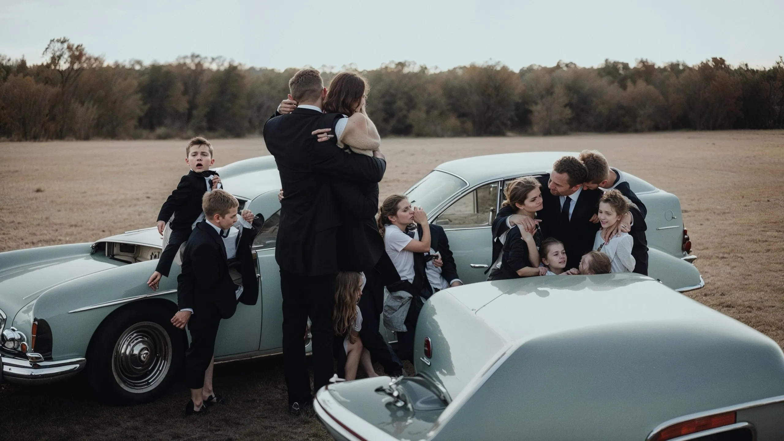 "Parting Ways" is an evocative piece from the "The Crossing" collection, capturing a poignant moment of farewell set against the backdrop of an expansive field. The scene is centered around a vintage luxury car, a symbolic vessel for journeys and transitions. A family is portrayed in the midst of parting embraces, their expressions a mix of affection and somber anticipation. The children, dressed in formal attire, add a touch of timeless elegance to the scene, with some looking on thoughtfully, others seemingly unaware of the gravity of the moment, highlighting the innocence of youth amidst the solemnity of farewells. The image's warm tones and the gentle landscape beyond speak to the bittersweet nature of goodbyes, suggesting both the end of an era and the beginning of a new chapter. This piece invites reflection on the bonds that hold us together even as paths diverge, a universal narrative of human connection and change.