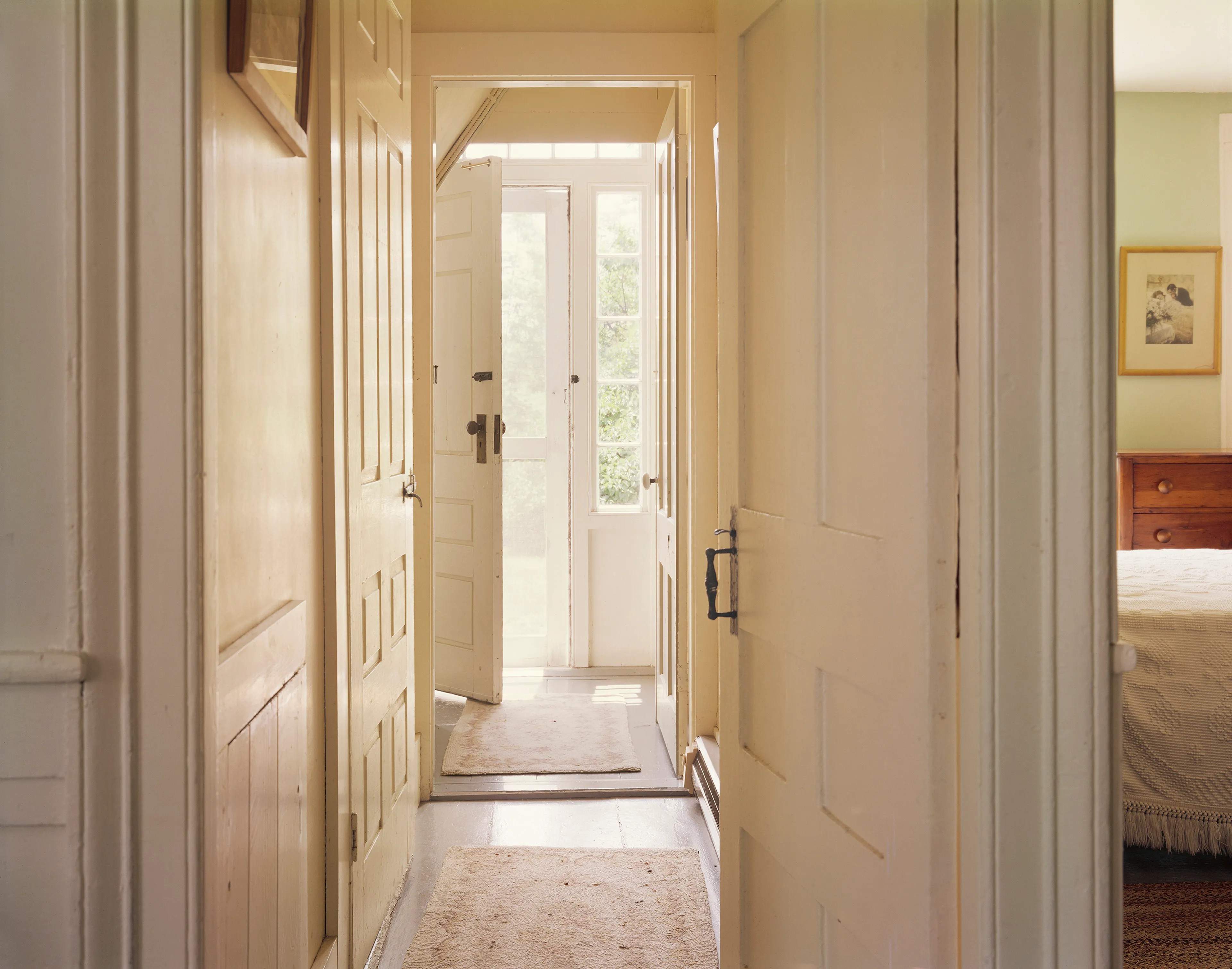 July 2, 1976: Hallway, house, interior, screen door, bedroom, sunlight, open door, carpets, white, rugs.

"I took myself off to Provincetown on Cape Cod so I could summer with my family, and learn how to see in 8x10, in which the image is upside down and reversed, while beginning to learn to use Time in seconds, rather than in 1000th of a second. Well, Cape Cod is not 5th Avenue, but the light out there on that 60-mile-long sandbar in the Atlantic is unlike light on the mainland. Every molecule of moisture refracts light like a prism; while on the mainland there is a particle of dirt in every drop of atmosphere. Once I recognized that, then everything changed. Light, in all its intensity and tone, became my subject. Just as in 35mm, you can only photograph where you are and what you see there." - Joel Meyerowitz.

Edition: 1 of 1