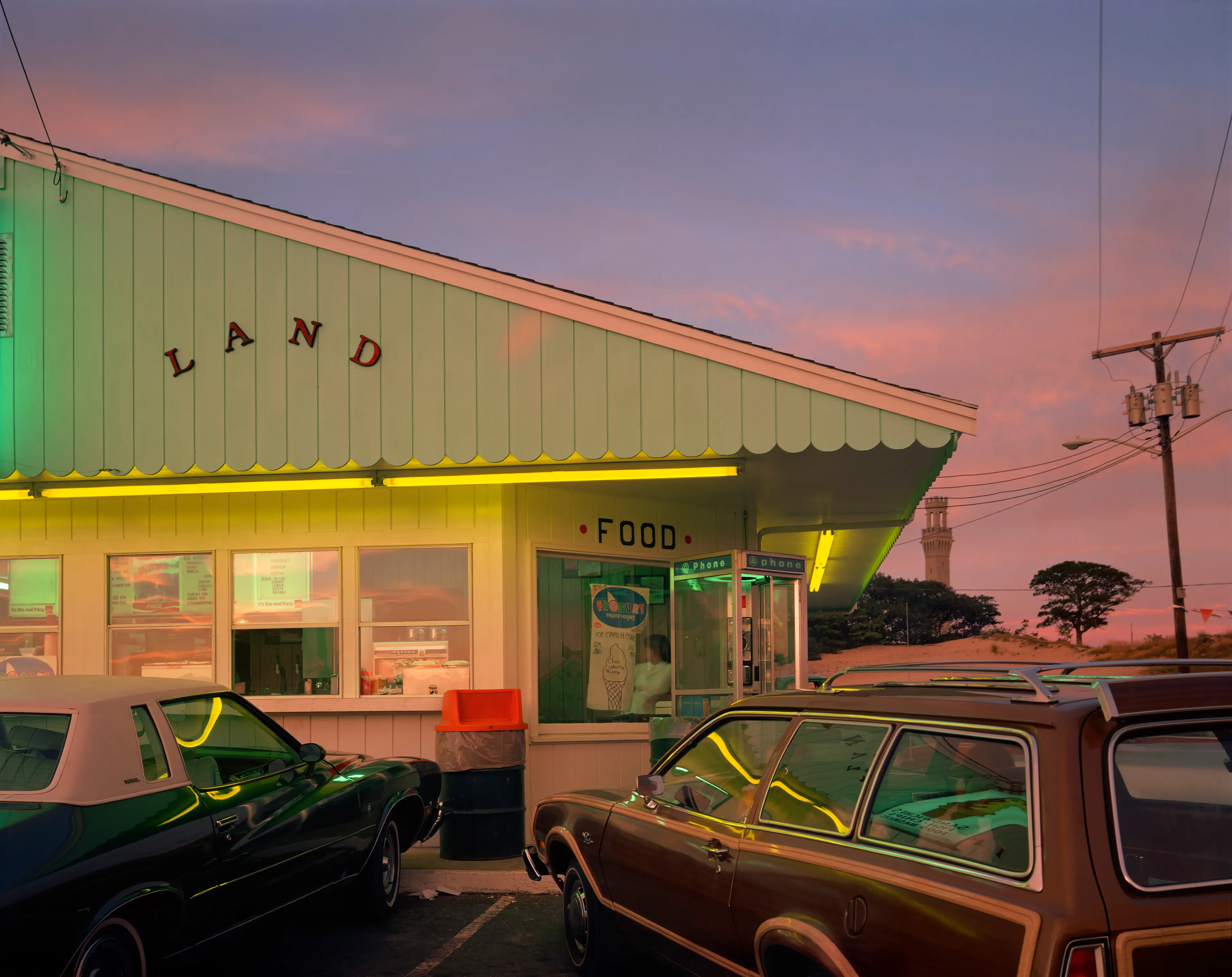 Aug. 19, 1976: Dairyland sunset, pilgrim monument, cars, drive-in, pink light, dusk, sign, neon, red, yellow.

"I took myself off to Provincetown on Cape Cod so I could summer with my family, and learn how to see in 8x10, in which the image is upside down and reversed, while beginning to learn to use Time in seconds, rather than in 1000th of a second. Well, Cape Cod is not 5th Avenue, but the light out there on that 60-mile-long sandbar in the Atlantic is unlike light on the mainland. Every molecule of moisture refracts light like a prism; while on the mainland there is a particle of dirt in every drop of atmosphere. Once I recognized that, then everything changed. Light, in all its intensity and tone, became my subject. Just as in 35mm, you can only photograph where you are and what you see there." - Joel Meyerowitz.

Edition: 1 of 1