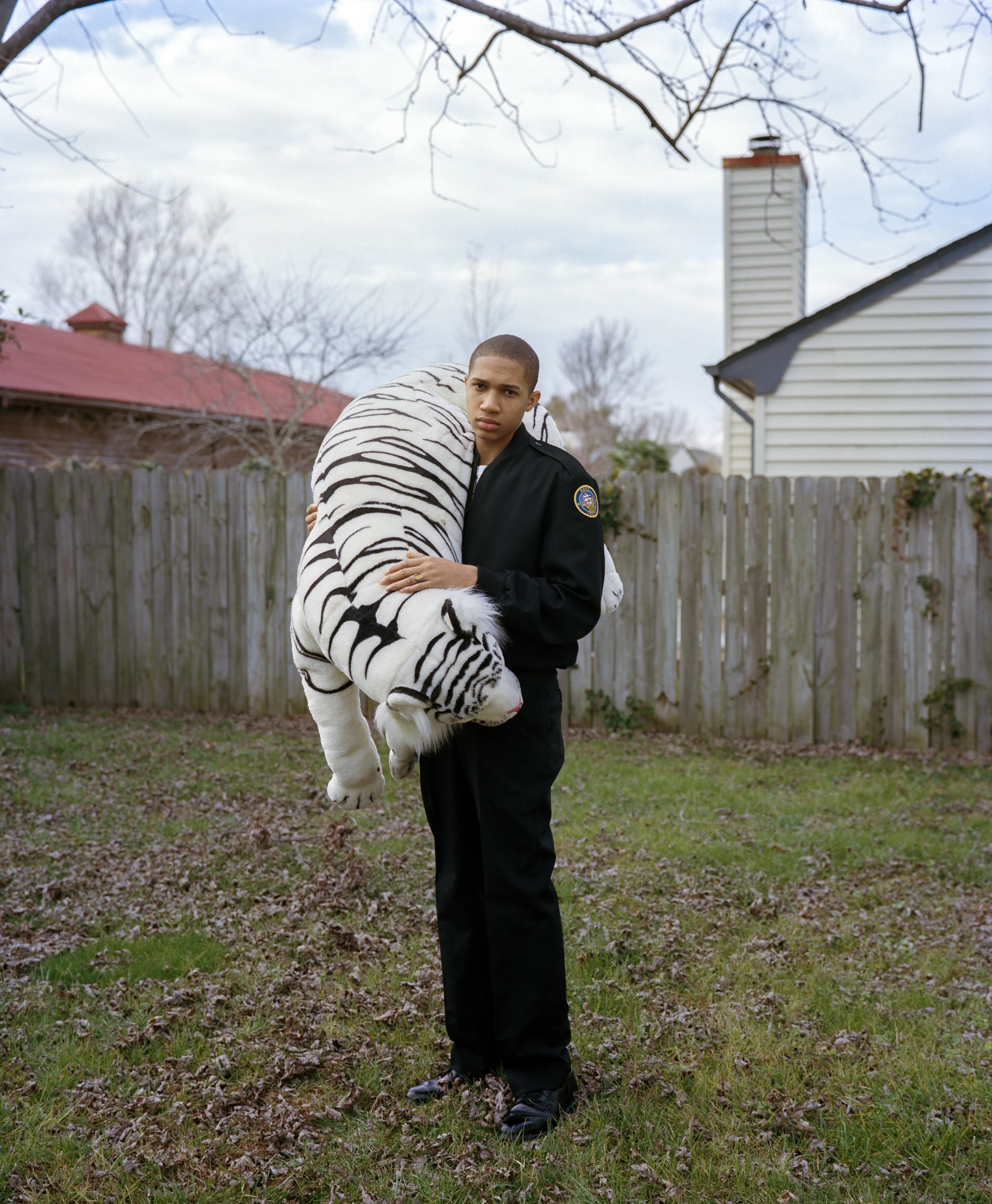 Right before I made the first image of Sharrod, when he went to his bedroom to change, his mother turned to me and said, “Whenever he puts on his uniform, I no longer see my son.”

In the winter of 2008 I met Sharrod, who was in his first year of high school and had recently enrolled in National Junior Reserve Officer’s Training Corps (NJROTC), a military preparatory program offered in high schools nationwide. After explaining my connection to the military and that I was an alum of the same high school that both Sharrod and his mother attended, I asked if I might photograph Sharrod from his freshman to senior year (2008-2012). They both agreed and over the course of the next four years, Sharrod played out his military fantasies for my camera. Sharrod also shared with me the photographs he was making with his cell phone and notebook doodles of weapon construction. These private images and examinations rub up against, color, and compliment the medium format images I’ve made providing the viewer a fuller image of Sharrod’s journey.

Over the course of making the images and video installations for "I slowly watched him disappear," I wondered about the process within which the military body is formed both literally but also psychologically, visually, and emotionally. What is the process of indoctrination and how does the heavy flow of military marketing messages — specifically in military towns— foreclose possibilities for a life beyond the uniform? Furthermore, can one photographically locate the transition from civilian to member of the military unit? 

"I slowly watched him disappear" is the first part of a multimedia “essay” including photographs, video installations, nonfiction films, curatorial projects, and texts which organize my meditations on the fantasy, construction, and deconstruction of the military body and its effects on the broader culture.  