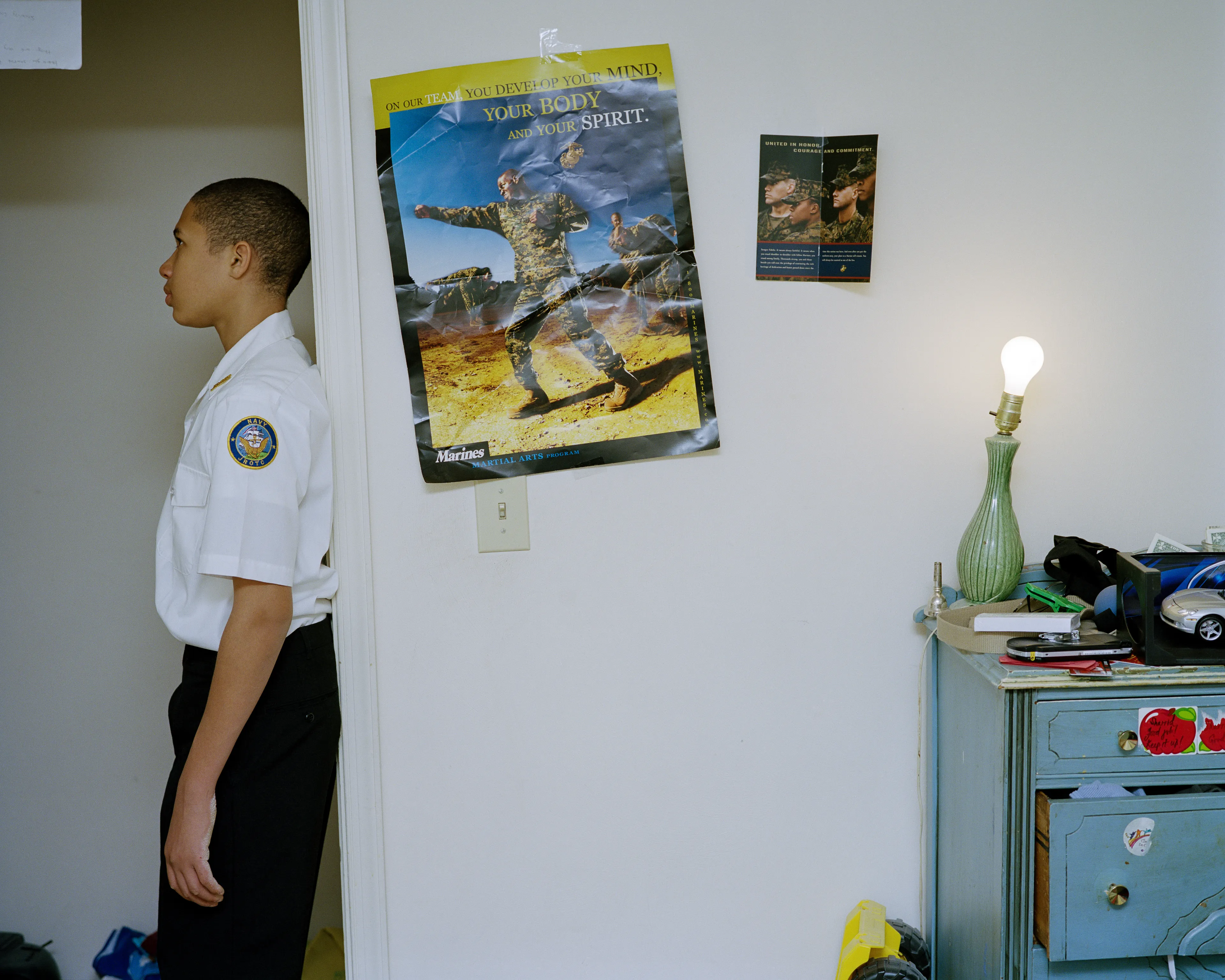 Right before I made the first image of Sharrod, when he went to his bedroom to change, his mother turned to me and said, “Whenever he puts on his uniform, I no longer see my son.”

In the winter of 2008 I met Sharrod, who was in his first year of high school and had recently enrolled in National Junior Reserve Officer’s Training Corps (NJROTC), a military preparatory program offered in high schools nationwide. After explaining my connection to the military and that I was an alum of the same high school that both Sharrod and his mother attended, I asked if I might photograph Sharrod from his freshman to senior year (2008-2012). They both agreed and over the course of the next four years, Sharrod played out his military fantasies for my camera. Sharrod also shared with me the photographs he was making with his cell phone and notebook doodles of weapon construction. These private images and examinations rub up against, color, and compliment the medium format images I’ve made providing the viewer a fuller image of Sharrod’s journey.

Over the course of making the images and video installations for "I slowly watched him disappear," I wondered about the process within which the military body is formed both literally but also psychologically, visually, and emotionally. What is the process of indoctrination and how does the heavy flow of military marketing messages — specifically in military towns— foreclose possibilities for a life beyond the uniform? Furthermore, can one photographically locate the transition from civilian to member of the military unit? 

"I slowly watched him disappear" is the first part of a multimedia “essay” including photographs, video installations, nonfiction films, curatorial projects, and texts which organize my meditations on the fantasy, construction, and deconstruction of the military body and its effects on the broader culture.  