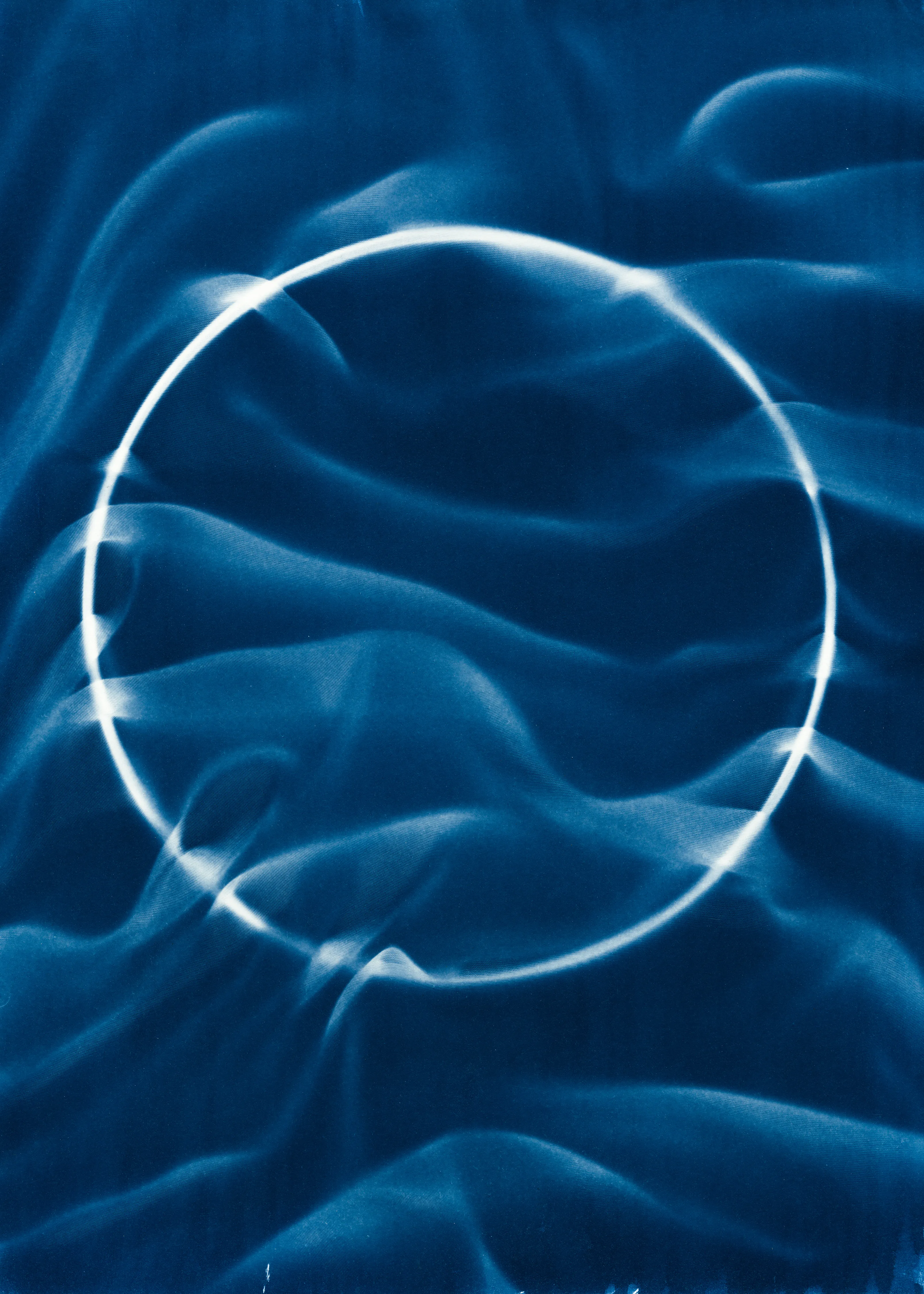 Beyond the Veil is simultaneously a melding of mediums as a means to sculpt with light, and an attempt to
capture the fabric of reality. I work with cyanotype, an alternative photography process that yields blue-
toned impressions when exposed to UV light. 
Cyanotype allows me to interact directly with light, one of the most subtle phenomena we experience day to day. Combined with sculpture, collage and drawing, the
cyanotype process is a powerful creative tool fueled by the sun. Working with light and shadow is to
become aware of how they describe our reality.

Created over the past eight months, this collection has been my safe haven from the world. A finger on the
pulse of something deeper than the chaotic rhythm of daily life, an album of captive sunlight and
experiences preserved in blue. The stillness of winter sunlight, silent rolling waves, a slow, even breath. I
hope you too can find solace here.