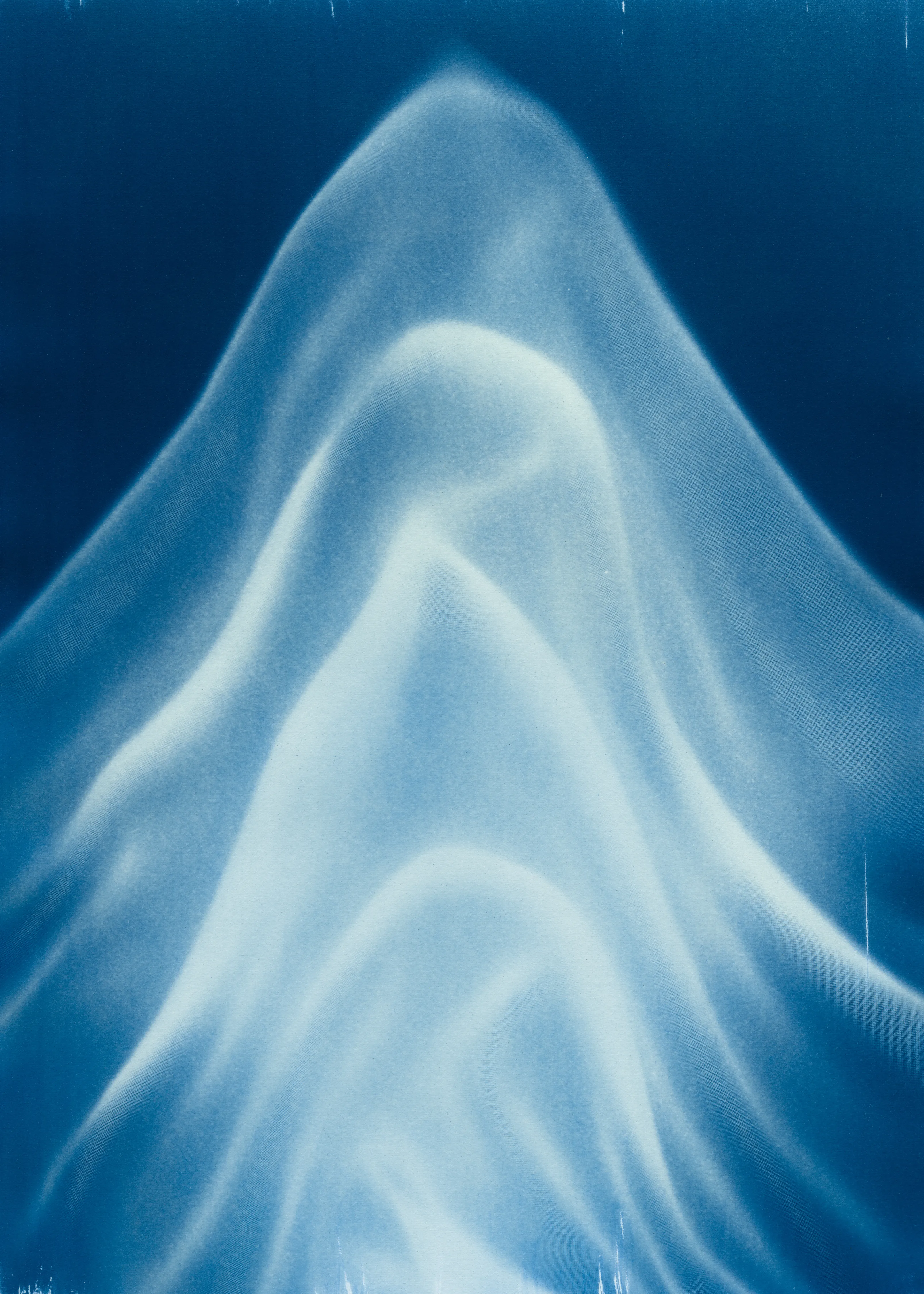 Beyond the Veil is simultaneously a melding of mediums as a means to sculpt with light, and an attempt to
capture the fabric of reality. I work with cyanotype, an alternative photography process that yields blue-
toned impressions when exposed to UV light. 
Cyanotype allows me to interact directly with light, one of the most subtle phenomena we experience day to day. Combined with sculpture, collage and drawing, the
cyanotype process is a powerful creative tool fueled by the sun. Working with light and shadow is to
become aware of how they describe our reality.

Created over the past eight months, this collection has been my safe haven from the world. A finger on the
pulse of something deeper than the chaotic rhythm of daily life, an album of captive sunlight and
experiences preserved in blue. The stillness of winter sunlight, silent rolling waves, a slow, even breath. I
hope you too can find solace here.
