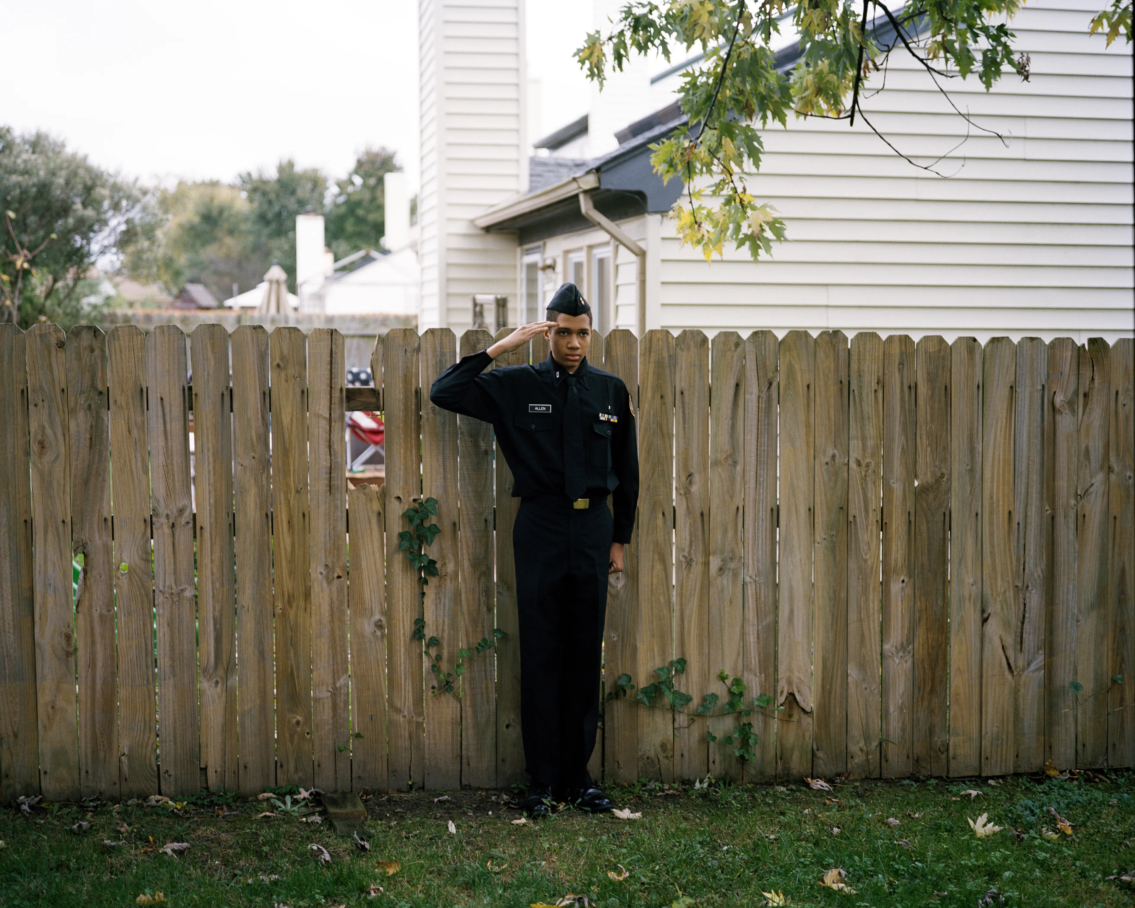 Right before I made the first image of Sharrod, when he went to his bedroom to change, his mother turned to me and said, “Whenever he puts on his uniform, I no longer see my son.”

In the winter of 2008 I met Sharrod, who was in his first year of high school and had recently enrolled in National Junior Reserve Officer’s Training Corps (NJROTC), a military preparatory program offered in high schools nationwide. After explaining my connection to the military and that I was an alum of the same high school that both Sharrod and his mother attended, I asked if I might photograph Sharrod from his freshman to senior year (2008-2012). They both agreed and over the course of the next four years, Sharrod played out his military fantasies for my camera. Sharrod also shared with me the photographs he was making with his cell phone and notebook doodles of weapon construction. These private images and examinations rub up against, color, and compliment the medium format images I’ve made providing the viewer a fuller image of Sharrod’s journey.

Over the course of making the images and video installations for "I slowly watched him disappear," I wondered about the process within which the military body is formed both literally but also psychologically, visually, and emotionally. What is the process of indoctrination and how does the heavy flow of military marketing messages — specifically in military towns— foreclose possibilities for a life beyond the uniform? Furthermore, can one photographically locate the transition from civilian to member of the military unit? 

"I slowly watched him disappear" is the first part of a multimedia “essay” including photographs, video installations, nonfiction films, curatorial projects, and texts which organize my meditations on the fantasy, construction, and deconstruction of the military body and its effects on the broader culture.  