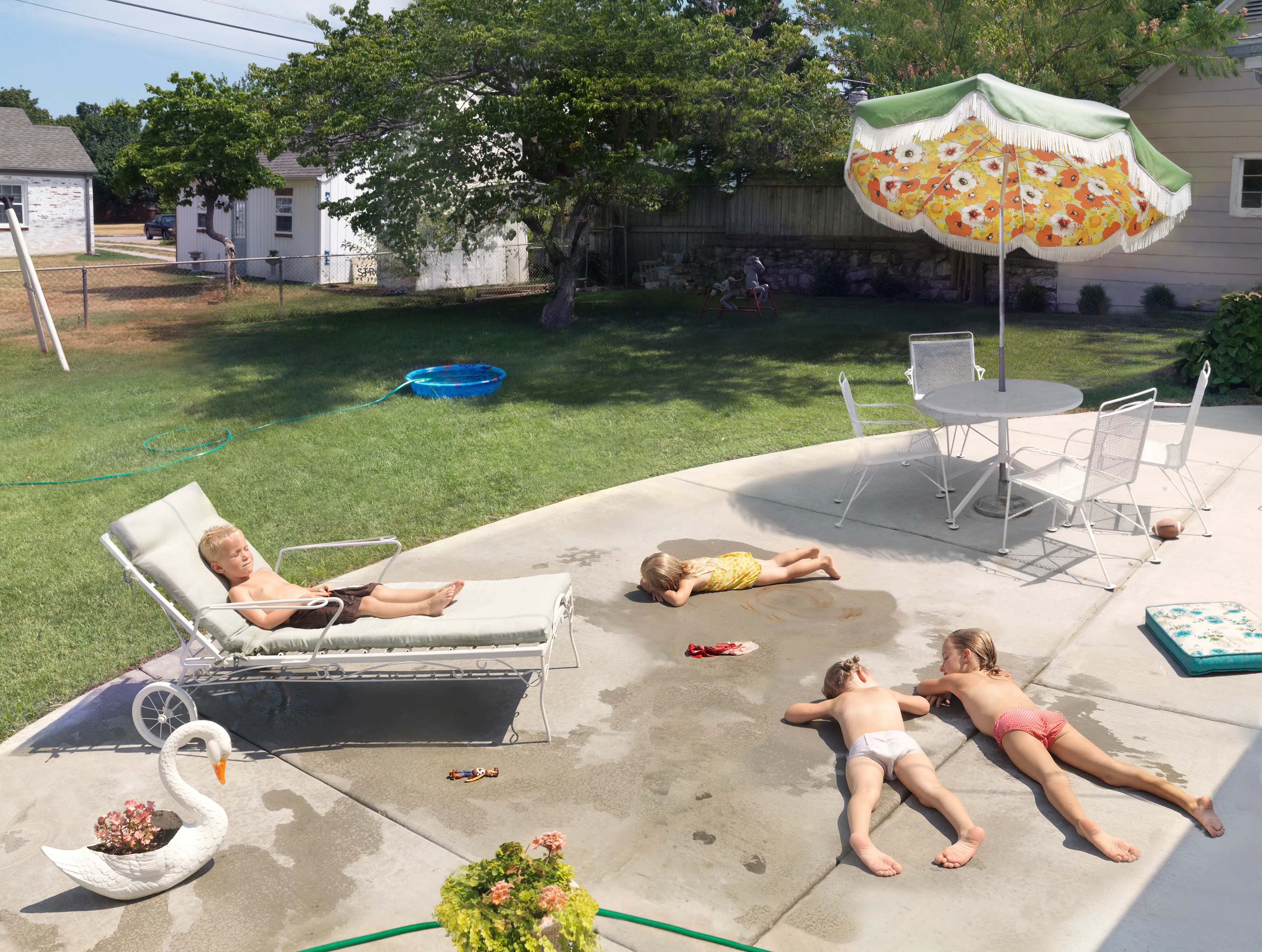 “I suppose I could make a work where the sun is shining, the mom is lying out in the grass, the kids are happy, and everything is perfect, but that wouldn’t interest me—and it wouldn’t be truthful. My aim is to create a more nuanced, subtly humorous and satirical portrait of the way we live today.” - Julie Blackmon

The playfully artful and chaotic elements present in the photographs of Julie Blackmon (American, b. 1966) are drawn from the everyday people and places of Blackmon’s daily routine in her hometown of Springfield, Missouri, which she describes as “a generic American town in the middle of the United States.” At first glance, the works may conjure backyard paradises of children at play; a closer look reveals children alone in backyards, garages, and neighborhoods, where the absence of adults suggests a looming potential for danger. The images brim with fantasy and subtle satire that capture a delicate balance between the darkness and charm of contemporary American life.

Blackmon carefully sets her scenes, but like film and theater
directors, she is in pursuit of unscripted moments that provoke,
disturb, and challenge the viewer. Some of the images reference
paintings by Dutch masters, French impressionists, and such modern painters as Hopper and Balthus, but they are updated with a satirical, penetrating eye and Blackmon’s belief that artful fiction can capture the truth more memorably than the truth itself.

#34