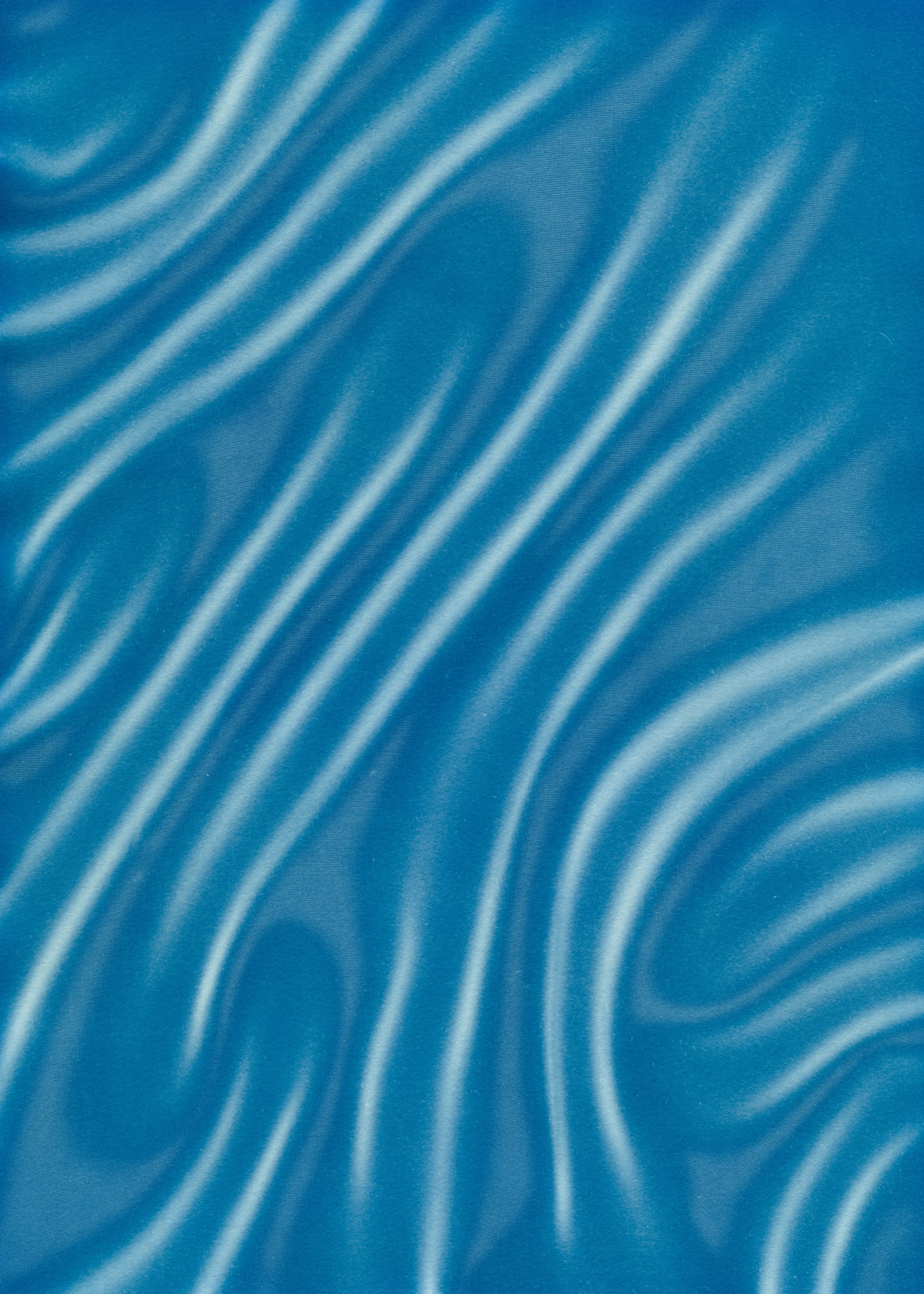 Beyond the Veil is simultaneously a melding of mediums as a means to sculpt with light, and an attempt to
capture the fabric of reality. I work with cyanotype, an alternative photography process that yields blue-
toned impressions when exposed to UV light. 
Cyanotype allows me to interact directly with light, one of the most subtle phenomena we experience day to day. Combined with sculpture, collage and drawing, the
cyanotype process is a powerful creative tool fueled by the sun. Working with light and shadow is to
become aware of how they describe our reality.

Created over the past eight months, this collection has been my safe haven from the world. A finger on the
pulse of something deeper than the chaotic rhythm of daily life, an album of captive sunlight and
experiences preserved in blue. The stillness of winter sunlight, silent rolling waves, a slow, even breath. I
hope you too can find solace here.