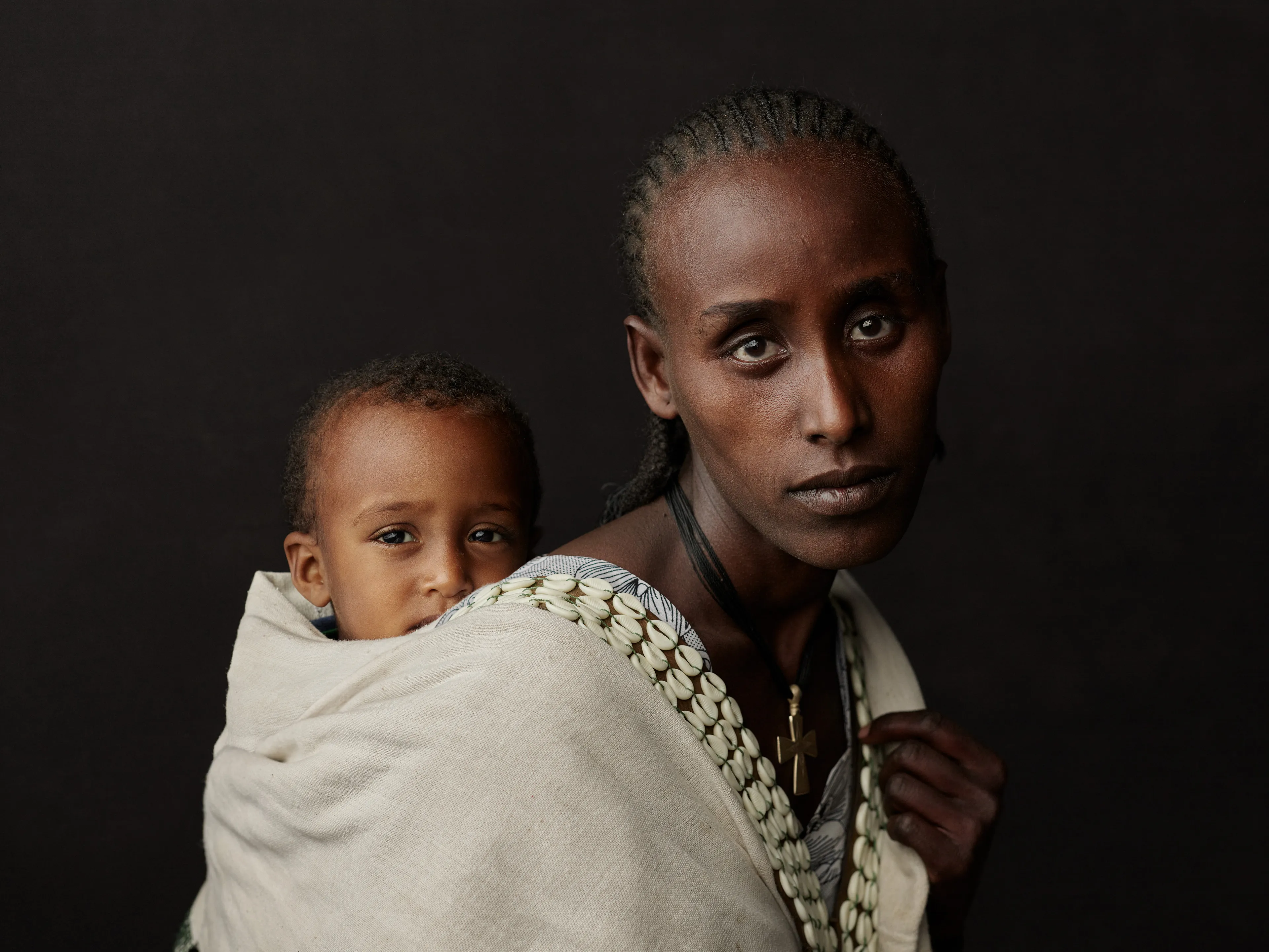 Joey L. returns to Quantum with Ethiopia - Portraits: a collection directly linked to his genesis drop during Season 1. For every environmental image from Joey’s first drop, there is a portrait companion.

“For years, we dragged our nomadic studio tent across almost every region of Ethiopia. In our tent, everyone was equal. We captured pure magic. Every kind of person entered and had their portrait taken. The tent was our little fantasy world. It was the Ethiopia that we dreamed of, even when the reality outside of it was sometimes stricken with searing pain. Each portrait was a tribute to a distinct region of the country. Disconnected cultural threads were woven together in a cohesive visual style in order to truly see Ethiopia— which itself is a modern nation state, but is also the sum of all the diverse people who inhabit it.”

Joey’s portraits alternating on red and black backdrops are the visual backbone of my forthcoming book “Ethiopia” (Insight Editions, January 2023), which compiles 13 years of work.

The tent itself is a metal frame modified with diffusion material made out of netela fabric, which is a hand-spun cotton perfected by Dorze craftspeople. Every portrait is created with natural light molded from the tent itself and photographed on location.

Amhara, Bilbala, 
Amhara Region, Ethiopia  
January 2021