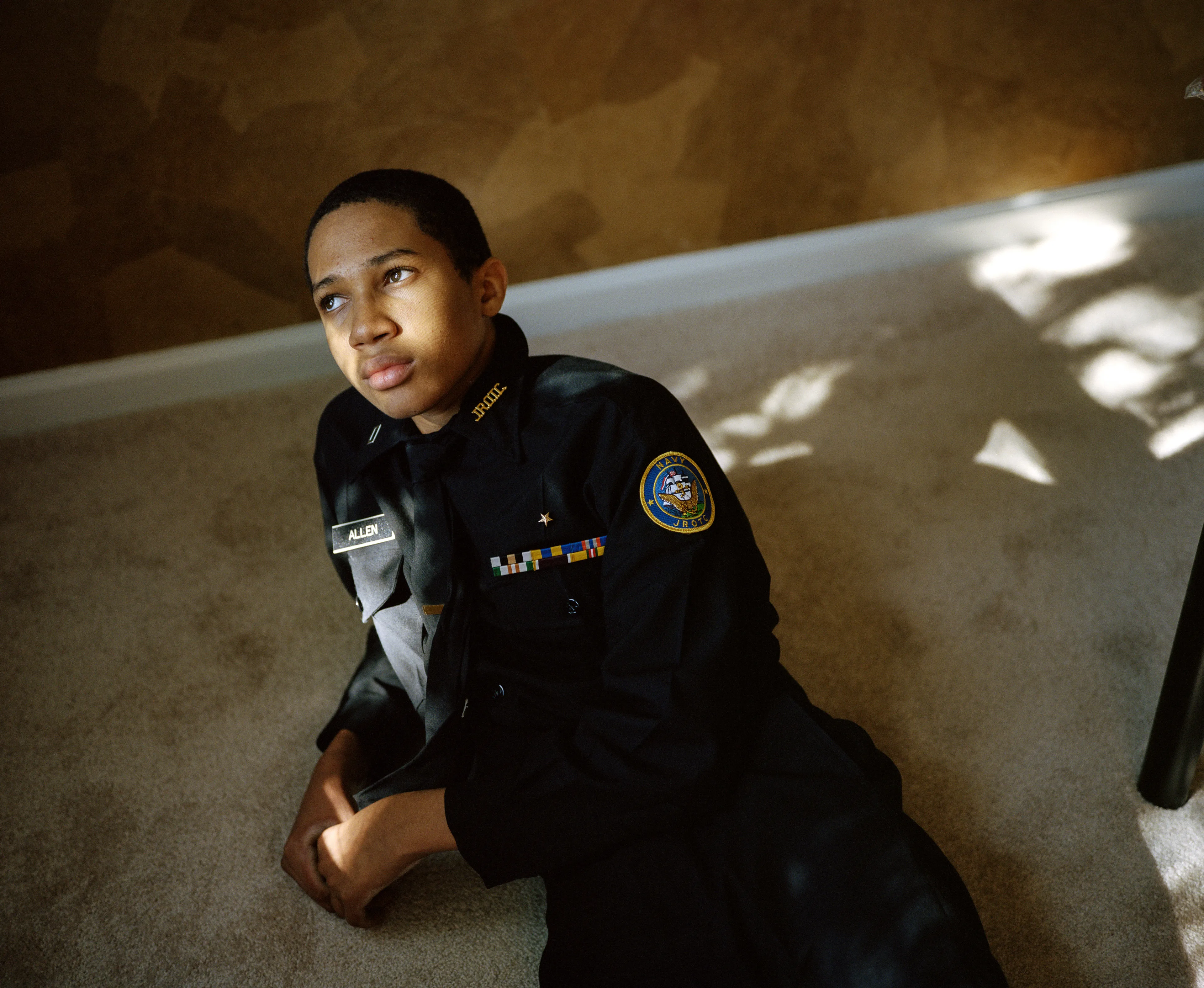 Right before I made the first image of Sharrod, when he went to his bedroom to change, his mother turned to me and said, “Whenever he puts on his uniform, I no longer see my son.”

In the winter of 2008 I met Sharrod, who was in his first year of high school and had recently enrolled in National Junior Reserve Officer’s Training Corps (NJROTC), a military preparatory program offered in high schools nationwide. After explaining my connection to the military and that I was an alum of the same high school that both Sharrod and his mother attended, I asked if I might photograph Sharrod from his freshman to senior year (2008-2012). They both agreed and over the course of the next four years, Sharrod played out his military fantasies for my camera. Sharrod also shared with me the photographs he was making with his cell phone and notebook doodles of weapon construction. These private images and examinations rub up against, color, and compliment the medium format images I’ve made providing the viewer a fuller image of Sharrod’s journey.

Over the course of making the images and video installations for "I slowly watched him disappear," I wondered about the process within which the military body is formed both literally but also psychologically, visually, and emotionally. What is the process of indoctrination and how does the heavy flow of military marketing messages — specifically in military towns— foreclose possibilities for a life beyond the uniform? Furthermore, can one photographically locate the transition from civilian to member of the military unit? 

"I slowly watched him disappear" is the first part of a multimedia “essay” including photographs, video installations, nonfiction films, curatorial projects, and texts which organize my meditations on the fantasy, construction, and deconstruction of the military body and its effects on the broader culture.  