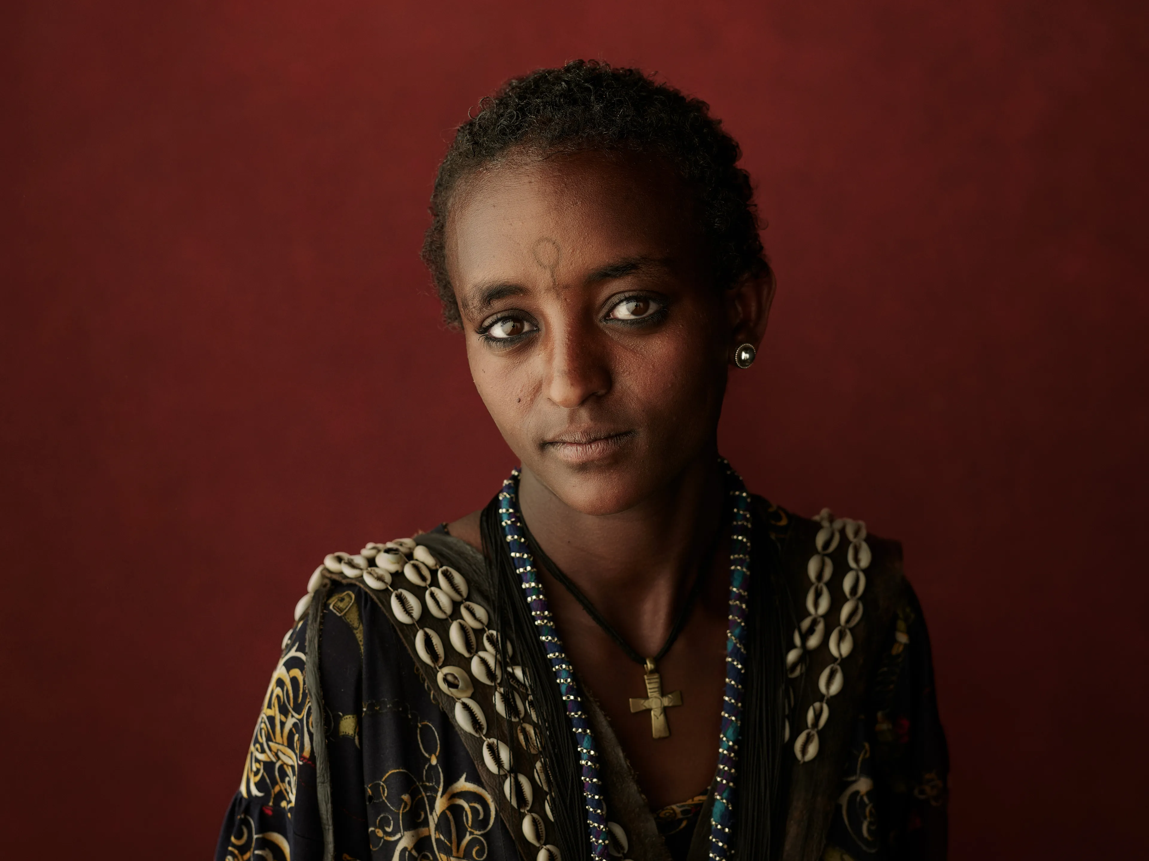 Joey L. returns to Quantum with Ethiopia - Portraits: a collection directly linked to his genesis drop during Season 1. For every environmental image from Joey’s first drop, there is a portrait companion.

“For years, we dragged our nomadic studio tent across almost every region of Ethiopia. In our tent, everyone was equal. We captured pure magic. Every kind of person entered and had their portrait taken. The tent was our little fantasy world. It was the Ethiopia that we dreamed of, even when the reality outside of it was sometimes stricken with searing pain. Each portrait was a tribute to a distinct region of the country. Disconnected cultural threads were woven together in a cohesive visual style in order to truly see Ethiopia— which itself is a modern nation state, but is also the sum of all the diverse people who inhabit it.”

Joey’s portraits alternating on red and black backdrops are the visual backbone of my forthcoming book “Ethiopia” (Insight Editions, January 2023), which compiles 13 years of work.

The tent itself is a metal frame modified with diffusion material made out of netela fabric, which is a hand-spun cotton perfected by Dorze craftspeople. Every portrait is created with natural light molded from the tent itself and photographed on location.

Amhara, Bilbala, 
Amhara Region, Ethiopia  
January 2021