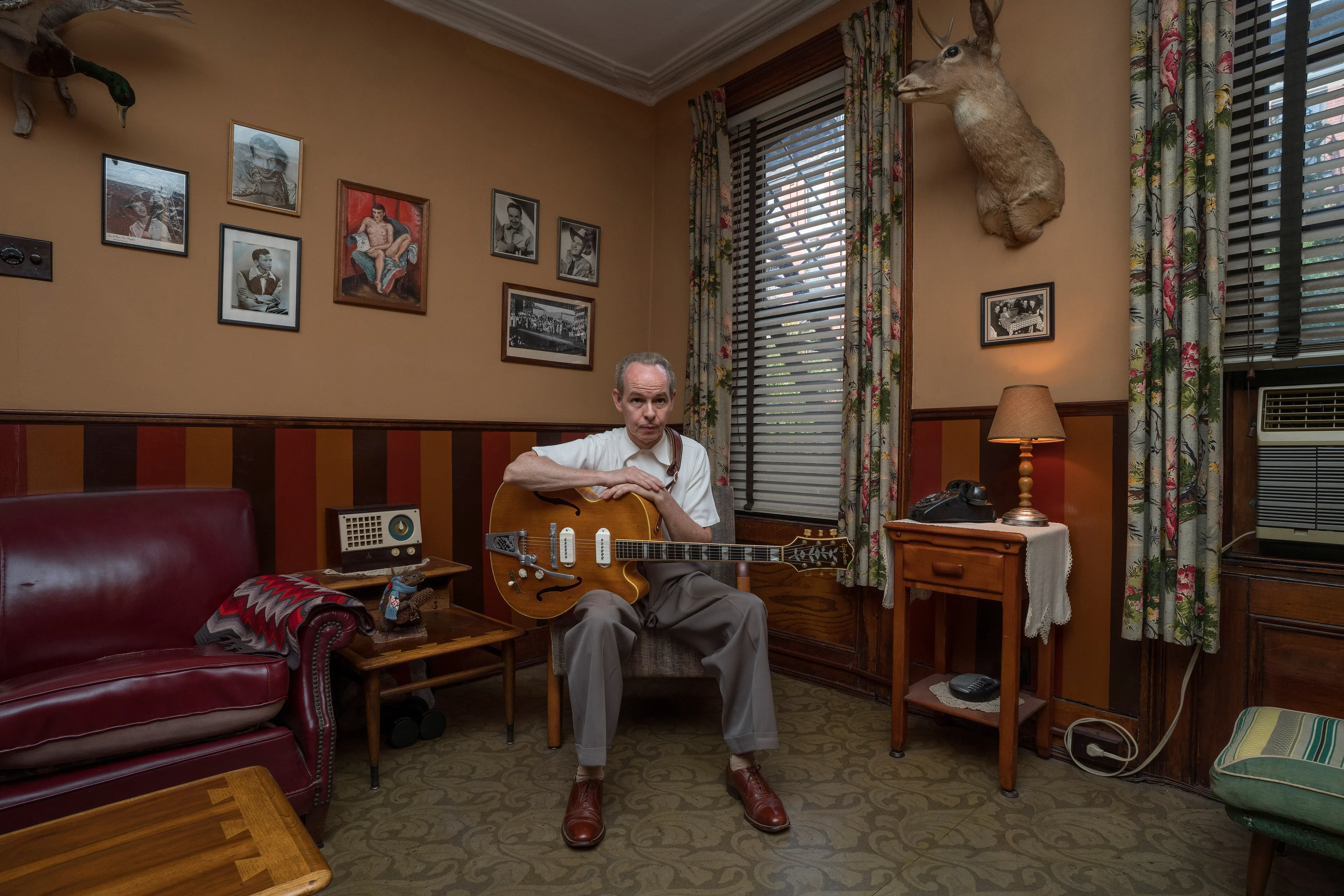For the past 30 years, Sally Davies has been documenting the streets of Manhattan. She’s watched neighborhoods negotiate with gentrification, post-9/11 anxiety, economic uncertainty, and a steady stream of “if I can make it there, I’ll make it anywhere” optimism. Davies has taken memorable photographs of ordinary doorways, wet curbs and corners, the glow of bar-grill signs, bodegas, bakery windows, wheelchairs on rooftops, incoming weather, graffiti, and vintage cars. As she has said, “You either fall in love with moonlight on a garbage bag or you hate it and move along.”*

Davies started the New Yorkers by shifting from her usual view of the urban outdoors to the idea of chronicling the spaces and stories of the natives and transplants who give the city its particular vitality. 

In these portraits, you will meet waitresses, musicians, cab drivers, painters, teachers, shopkeepers, writers, designers, producers, parents, a gossip columnist, and a psychic to the stars, among others. They are singularly sensational, and they attest to multiple jobs, friendships, marriages, divorces, children, and pets. Young and old, straight and gay, casual and formal; they pose in cramped kitchens and elegant living rooms, laying on beds, sitting in bathtubs, surrounded by the surfaces and souvenirs of living. There is an abundance of brick, wood, leather, and metal, and collections of refrigerator magnets, religious and street art, books, Pez dispensers, vinyl records, and plants.

These photographs and texts speak to what all New Yorkers understand—to live in this city is to embrace struggle, sacrifice, love, and change. When I spoke with Davies over breakfast in February 2020, I asked her what this project reveals. She said, “This is the end of an era.” That comment has returned to me repeatedly. This book went to print during a pandemic that stopped the world as we knew it. We were in our homes for hours on end, adapting to new habits, while thinking and feeling deeply about where and how we live. These New York people were right on time.

by Stuart Horodner
*Sally Davies in Michael Ernest Sweet’s “Photographer Sally Davies Discusses Women Street Photographers,” HuffPost (December 15, 2015) 

Photographed at his East Village apartment on August 22, 2019.
