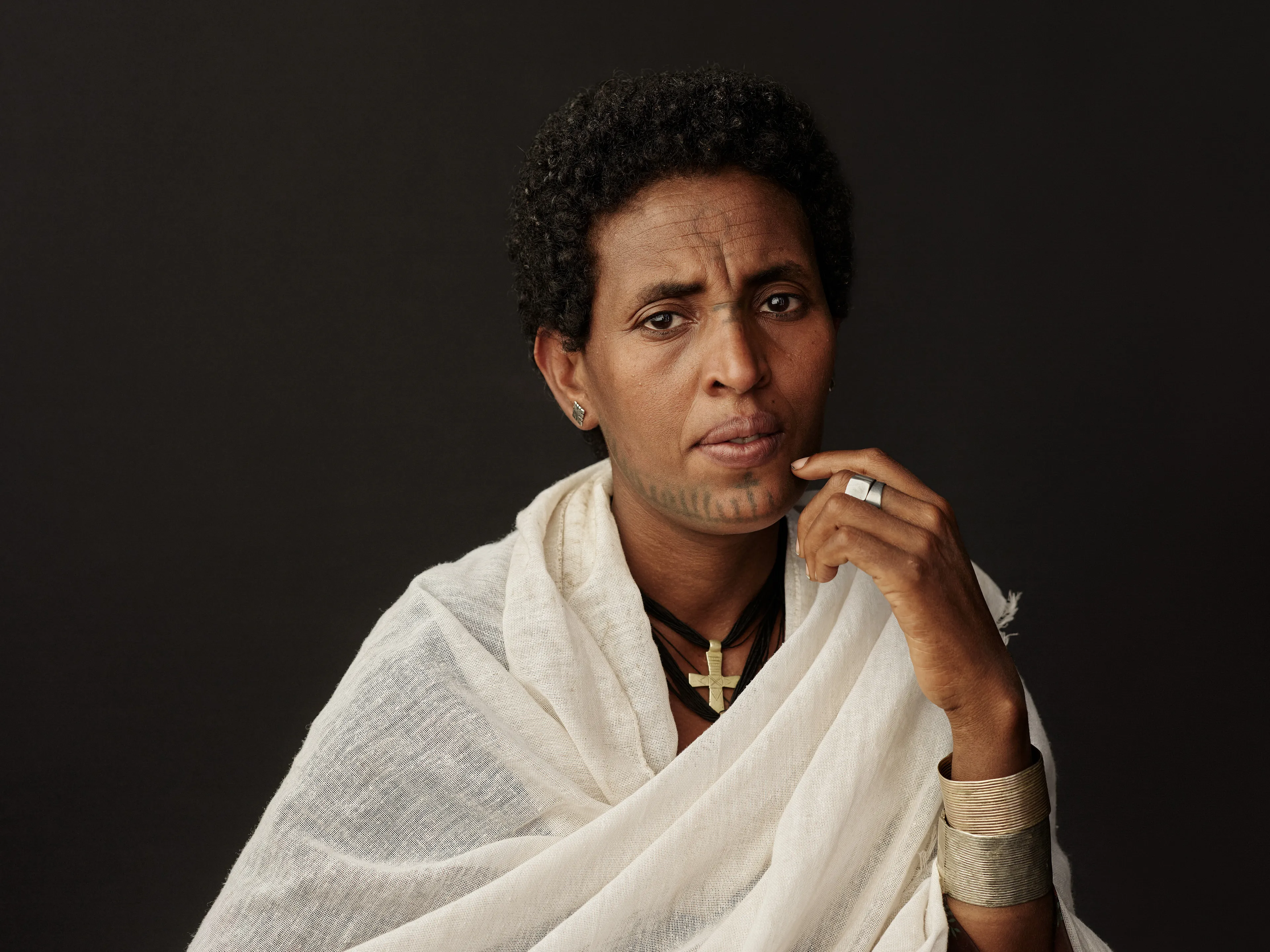 Joey L. returns to Quantum with Ethiopia - Portraits: a collection directly linked to his genesis drop during Season 1. For every environmental image from Joey’s first drop, there is a portrait companion.

“For years, we dragged our nomadic studio tent across almost every region of Ethiopia. In our tent, everyone was equal. We captured pure magic. Every kind of person entered and had their portrait taken. The tent was our little fantasy world. It was the Ethiopia that we dreamed of, even when the reality outside of it was sometimes stricken with searing pain. Each portrait was a tribute to a distinct region of the country. Disconnected cultural threads were woven together in a cohesive visual style in order to truly see Ethiopia— which itself is a modern nation state, but is also the sum of all the diverse people who inhabit it.”

Joey’s portraits alternating on red and black backdrops are the visual backbone of my forthcoming book “Ethiopia” (Insight Editions, January 2023), which compiles 13 years of work.

The tent itself is a metal frame modified with diffusion material made out of netela fabric, which is a hand-spun cotton perfected by Dorze craftspeople. Every portrait is created with natural light molded from the tent itself and photographed on location.

Lalibela, Amhara Region, Ethiopia 
January 2021
