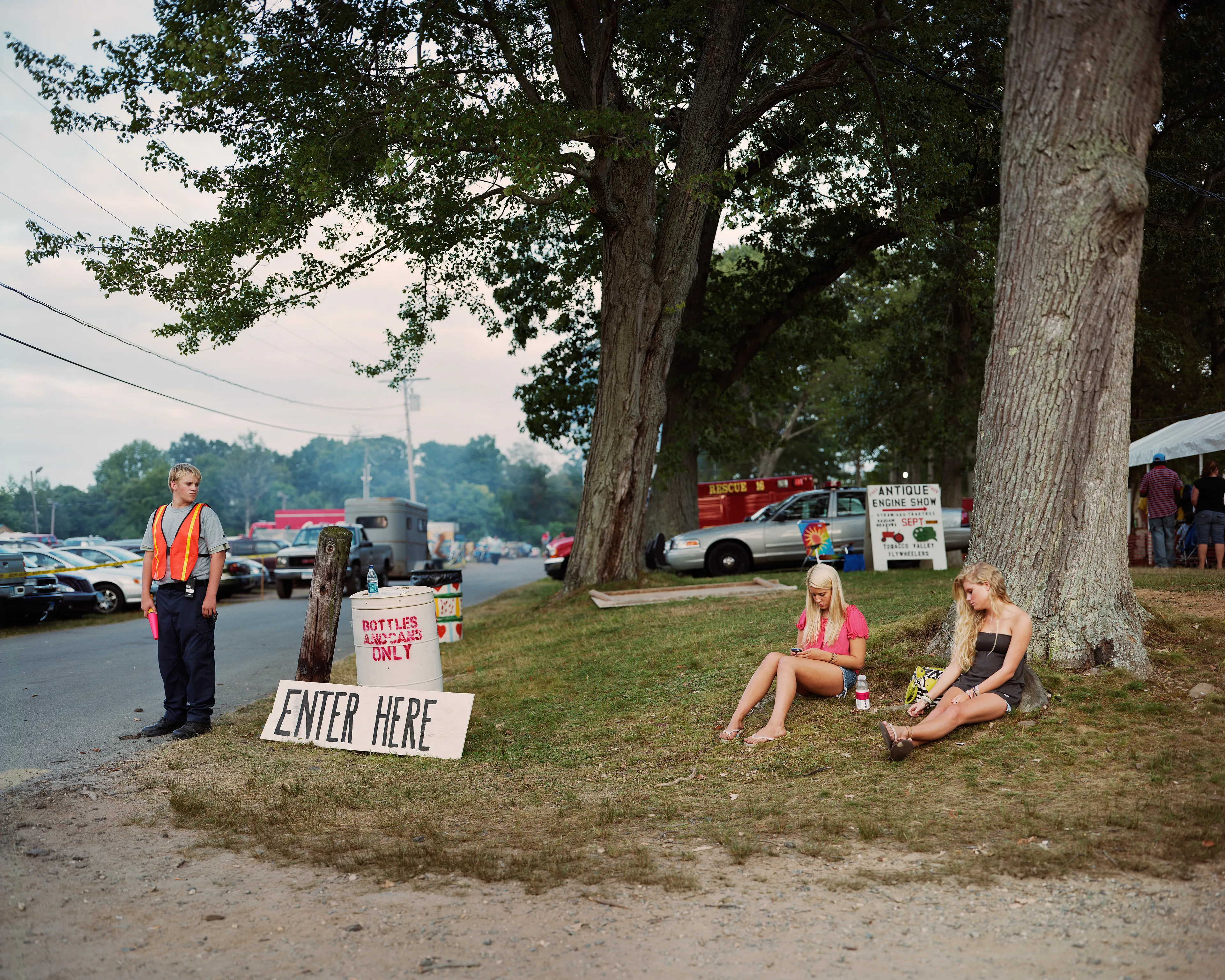 County fairs conjure ideas of tilt-a-whirls, stuffed animals, cotton candy, and blue ribbons. Rooted in local agricultural practices, fairs have been a ubiquitous part of American life for two centuries. In a reassuring way, they seem impervious to economic, technological, or fashion trends. For better or for worse, fairs look the same through the decades.

Though they are places to meet each other, there sure is a lot of loneliness at the fair. The series County Fair captures that duality: an adolescent boy looks up at the woman working the Hot Dog on a Stick stand as if she were a museum diorama; a little red haired girl haltingly befriends a robot; young couples, leaning and draped over each other, hide from the world in plain sight.


In my pictures, the dizzying atmosphere, colorfully decorated to provide amusement and distraction, is imbued with sadness and longing. These feelings, which permeate society, are laid bare at the fair. Sadness and longing circulate, intersect and incubate in the confined space between the ticket booths and the craft barns. People come out to participate and show, to see and be seen. Ultimately, connection remains elusive. 

