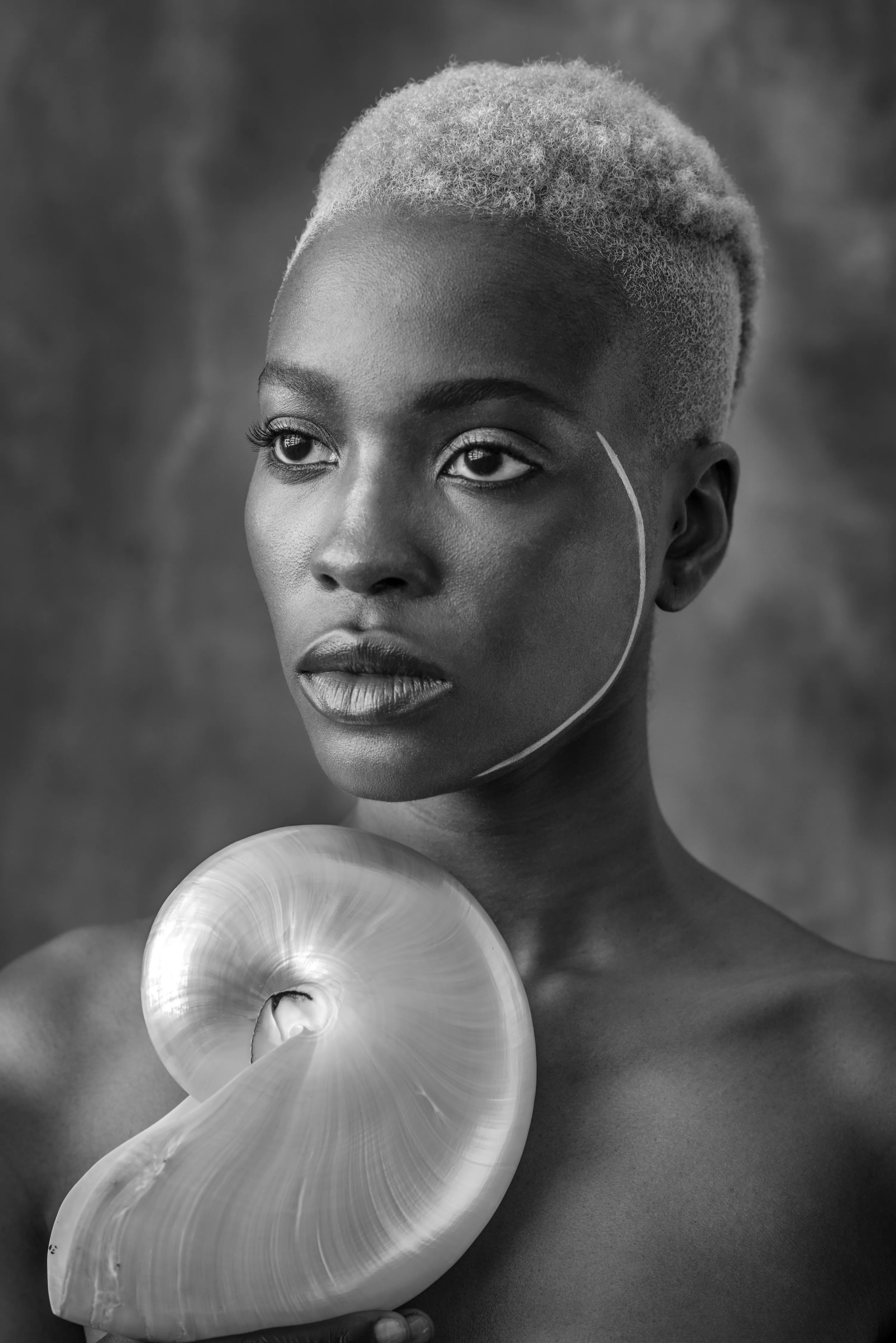 For centuries, the art world was seen through the eyes of a small few who, under a patriarchal society, chose the aesthetic and the narrative—and whose main depiction of the sacred female body was as an objectified and sexualized woman. 

Delphine Diallo aims to change this dynamic. Her intention is for every woman she photographs to feel the image she makes of them is a personal gift. “I am not taking pictures, I am giving pictures,” as Diallo puts it. By engaging in intimate conversations with her subjects, Delphine removes the sense of vulnerability that often comes with being photographed. Working with body painters and jewelry and mask makers, Diallo also uses traditional mythology and spiritual symbols to empower her subjects. Her portraiture is all about connection and exchange. She believes women are deep beings and connects with them on an emotional level. The French-Senegalese photographer spends more time speaking with her subjects than photographing them. 

Diallo’s photographs are never discriminating, yet deeply communicative, and portray women beyond judgment, soaking up their limitless beauty. Diallo's works are meant to encourage every woman to write a personal narrative, to take a stand, to have a firm voice. No preparatory models, sketches, or plans lay behind her photographs, which depict only outstanding feminine painted bodies. It is all a part of the vision flowing out of the artist's mind, grounded in her right brain hemisphere, predominant in her energetic and vibrant personality. 

Drawing elements from eastern mythology and philosophy, whilst always ennobling and empowering women, her practice is reminiscent of Oriental 19th-century painting. Looking at Krishnamurti, Frantz Fanon, Joseph Campbell, Bruce Lee, Aimé Césaire, and A.D. Wilson as deep inspirational sources, her photographs raise awareness, appealing to all women to awaken their senses. Diallo immerses herself in the realm of the feminine universe and her eloquent portraiture technique unveils and stirs unexplored emotion and insight meant to reach beyond appearances. 

“We are in constant search for wonder and growth. I see art as a vessel to express consciousness and as an access to diffuse wisdom, enlightenment, fear, beauty, ugliness, mystery, faith, strength, fearlessness, and universal matter”.

Artist: Delphine Diallo
Date: 2016