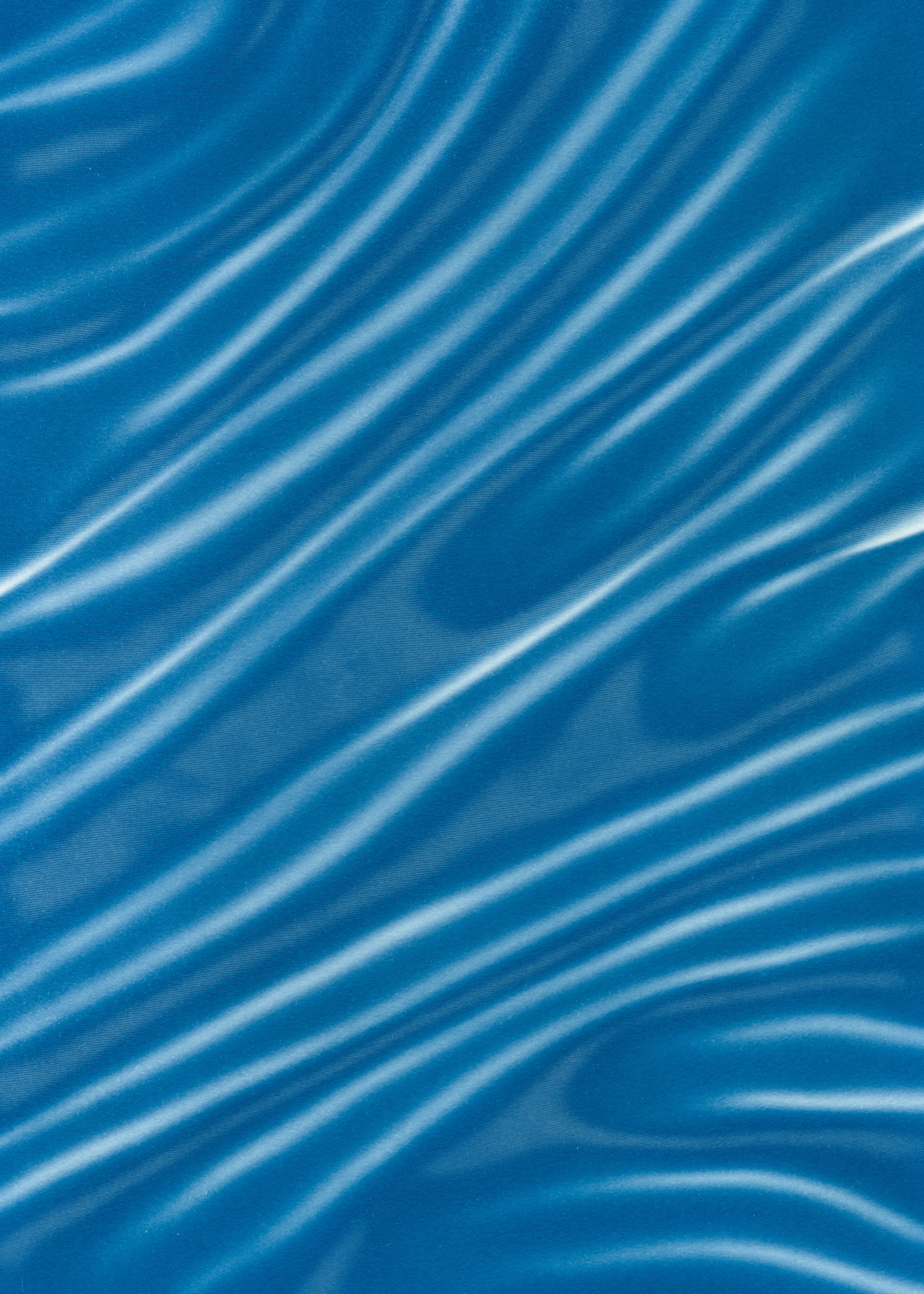 Beyond the Veil is simultaneously a melding of mediums as a means to sculpt with light, and an attempt to
capture the fabric of reality. I work with cyanotype, an alternative photography process that yields blue-
toned impressions when exposed to UV light. 
Cyanotype allows me to interact directly with light, one of the most subtle phenomena we experience day to day. Combined with sculpture, collage and drawing, the
cyanotype process is a powerful creative tool fueled by the sun. Working with light and shadow is to
become aware of how they describe our reality.

Created over the past eight months, this collection has been my safe haven from the world. A finger on the
pulse of something deeper than the chaotic rhythm of daily life, an album of captive sunlight and
experiences preserved in blue. The stillness of winter sunlight, silent rolling waves, a slow, even breath. I
hope you too can find solace here.