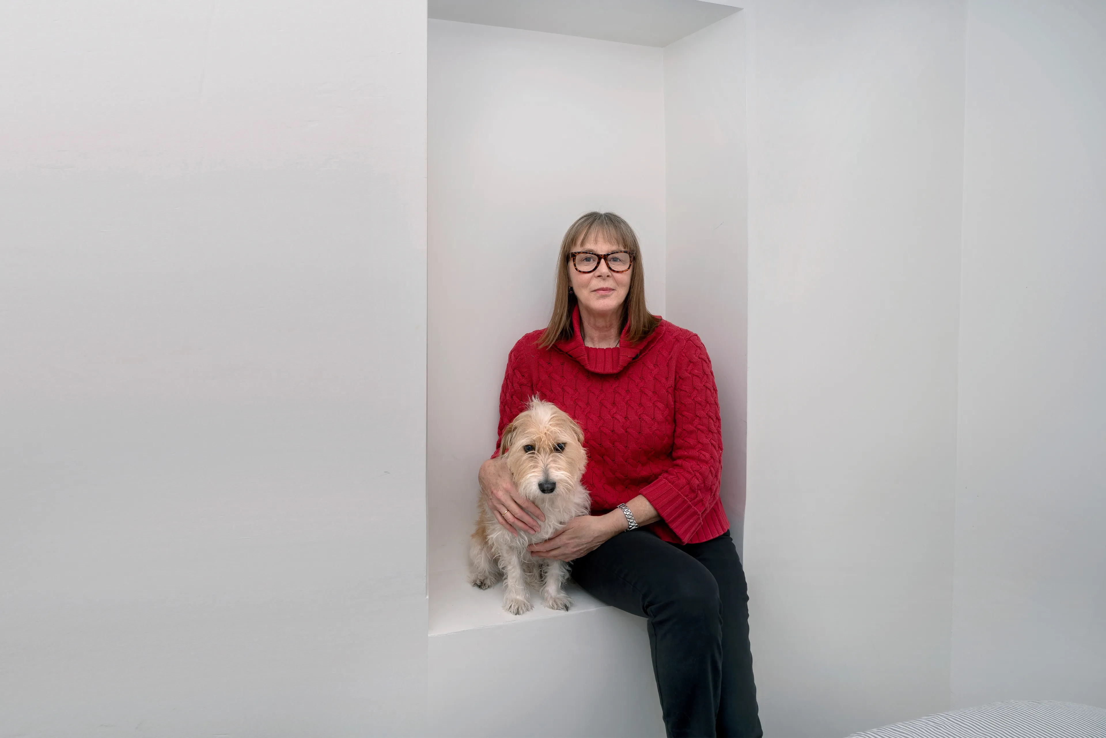 For the past 30 years, Sally Davies has been documenting the streets of Manhattan. She’s watched neighborhoods negotiate with gentrification, post-9/11 anxiety, economic uncertainty, and a steady stream of “if I can make it there, I’ll make it anywhere” optimism. Davies has taken memorable photographs of ordinary doorways, wet curbs and corners, the glow of bar-grill signs, bodegas, bakery windows, wheelchairs on rooftops, incoming weather, graffiti, and vintage cars. As she has said, “You either fall in love with moonlight on a garbage bag or you hate it and move along.”*

Davies started the New Yorkers by shifting from her usual view of the urban outdoors to the idea of chronicling the spaces and stories of the natives and transplants who give the city its particular vitality. 

In these portraits, you will meet waitresses, musicians, cab drivers, painters, teachers, shopkeepers, writers, designers, producers, parents, a gossip columnist, and a psychic to the stars, among others. They are singularly sensational, and they attest to multiple jobs, friendships, marriages, divorces, children, and pets. Young and old, straight and gay, casual and formal; they pose in cramped kitchens and elegant living rooms, laying on beds, sitting in bathtubs, surrounded by the surfaces and souvenirs of living. There is an abundance of brick, wood, leather, and metal, and collections of refrigerator magnets, religious and street art, books, Pez dispensers, vinyl records, and plants.

These photographs and texts speak to what all New Yorkers understand—to live in this city is to embrace struggle, sacrifice, love, and change. When I spoke with Davies over breakfast in February 2020, I asked her what this project reveals. She said, “This is the end of an era.” That comment has returned to me repeatedly. This book went to print during a pandemic that stopped the world as we knew it. We were in our homes for hours on end, adapting to new habits, while thinking and feeling deeply about where and how we live. These New York people were right on time.

by Stuart Horodner
*Sally Davies in Michael Ernest Sweet’s “Photographer Sally Davies Discusses Women Street Photographers,” HuffPost (December 15, 2015) 

Photographed with her dog Lilli at her Lower East Side apartment on January 4, 2020.
