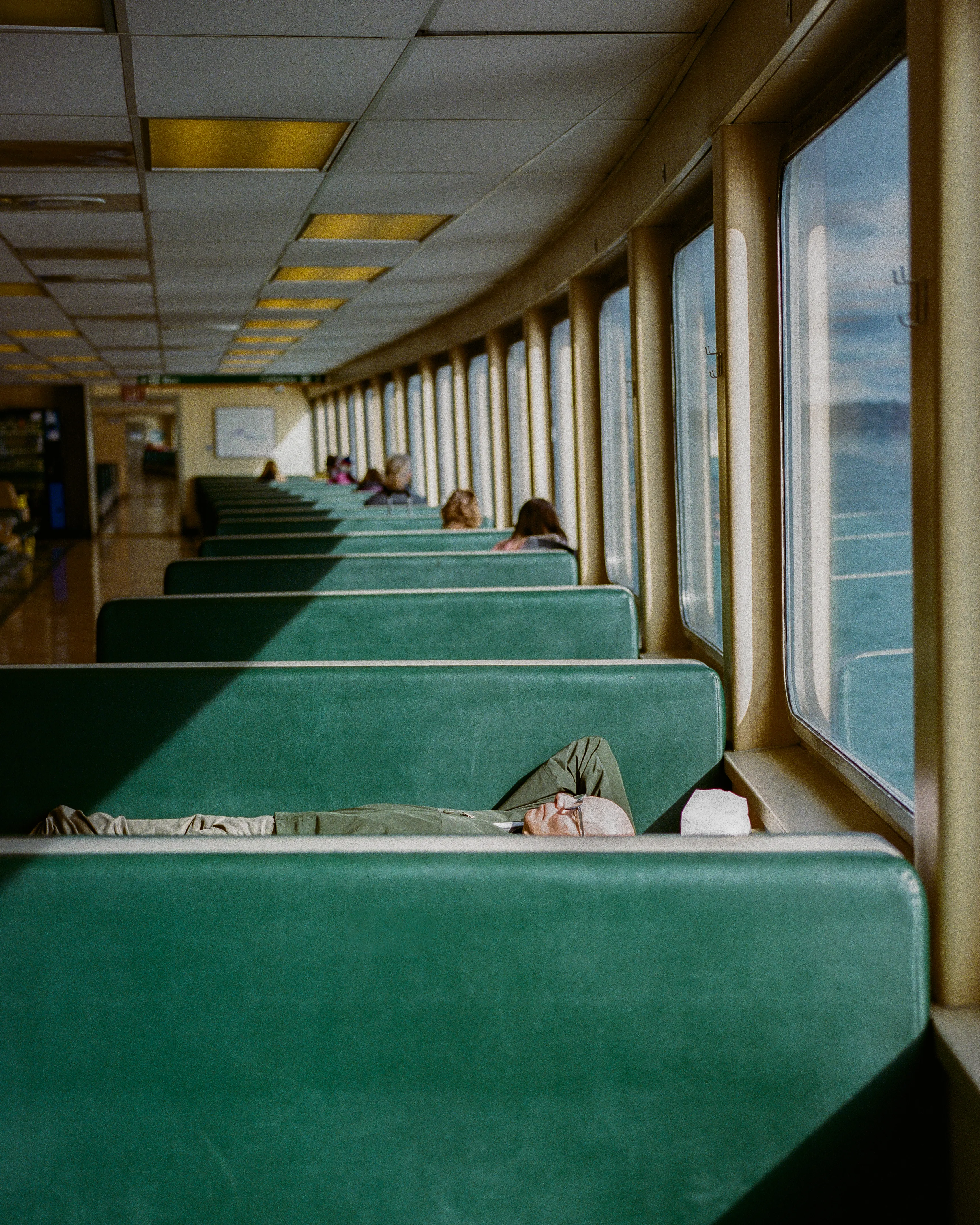 Between Bremerton and Seattle, a passenger finds comfort in the sunlight.