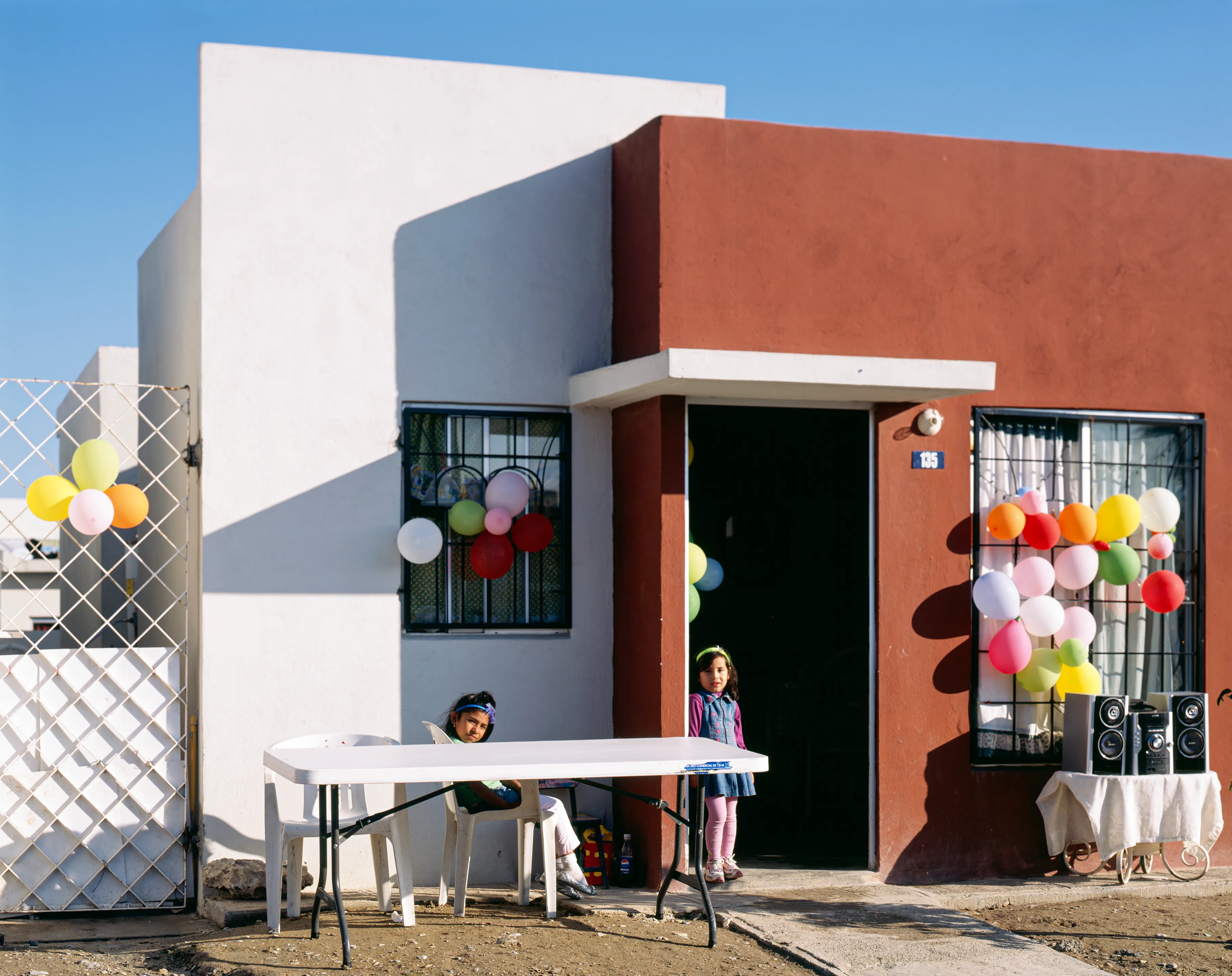 Birthday party in Juárez, Nuevo León, Mexico, 2005-2010. This image is part of a 5-year project called Suburbia Mexicana. During the first 10 years of the 21st Century, Mexico put forward a housing project that resulted in the construction of hundreds of thousands of homes around my hometown of Monterrey. These are the people who dared to dream to own a new home. I encountered them in their new suburbs and asked them to be part of the representation of a changing landscape we were both living through at that time.  All images were done with a large format 4x5 film camera.