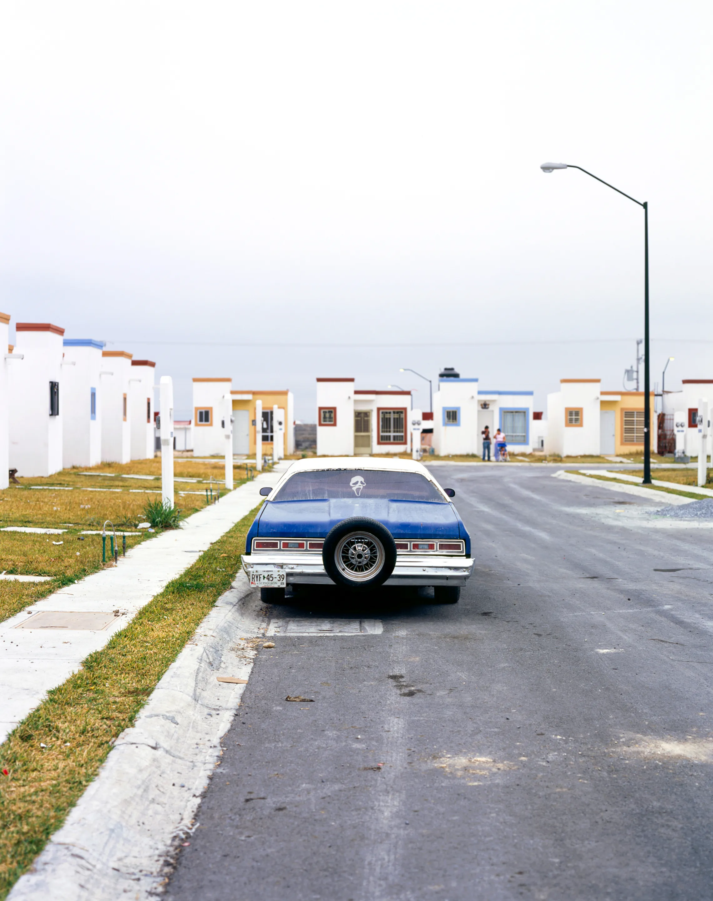 Old Car in Suburb, Juárez, Nuevo León, Mexico, 2005-2010. This image is part of a 5-year project called Suburbia Mexicana. During the first 10 years of the 21st Century, Mexico put forward a housing project that resulted in the construction of hundreds of thousands of homes around my hometown of Monterrey. These are the people who dared to dream to own a new home. I encountered them in their new suburbs and asked them to be part of the representation of a changing landscape we were both living through at that time.  All images were done with a large format 4x5 film camera.