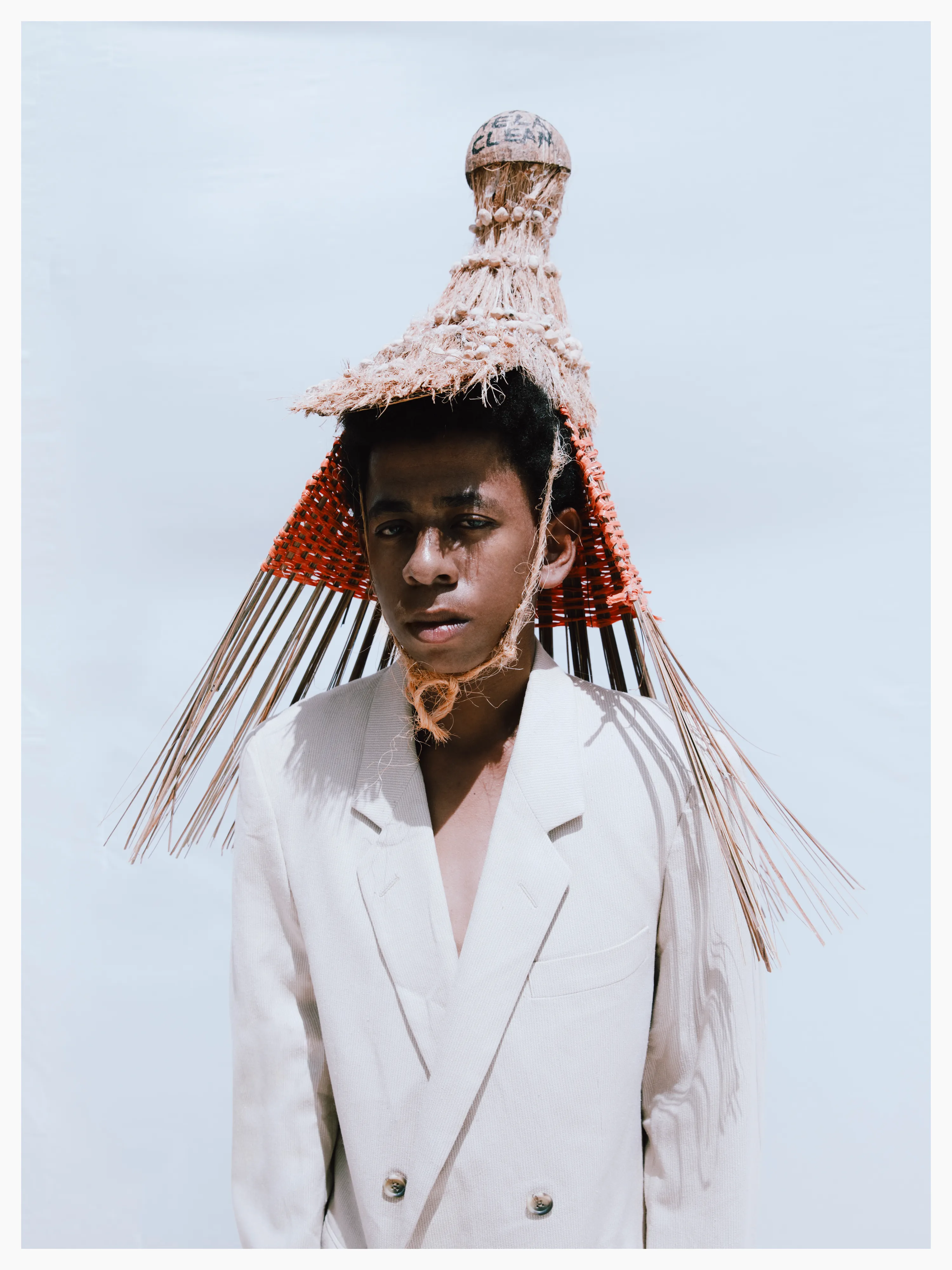 Mirza’s hat is inspired by the Kenyan Makuti thatch roof h ouse, and is made from natural fibres; coconut leaves, husks, and palm reeds, interwoven with re-purposed plastic string. The coconut shell crown reads “Keep Shela Clean”.

Photographed by me, styled by Louise Ford