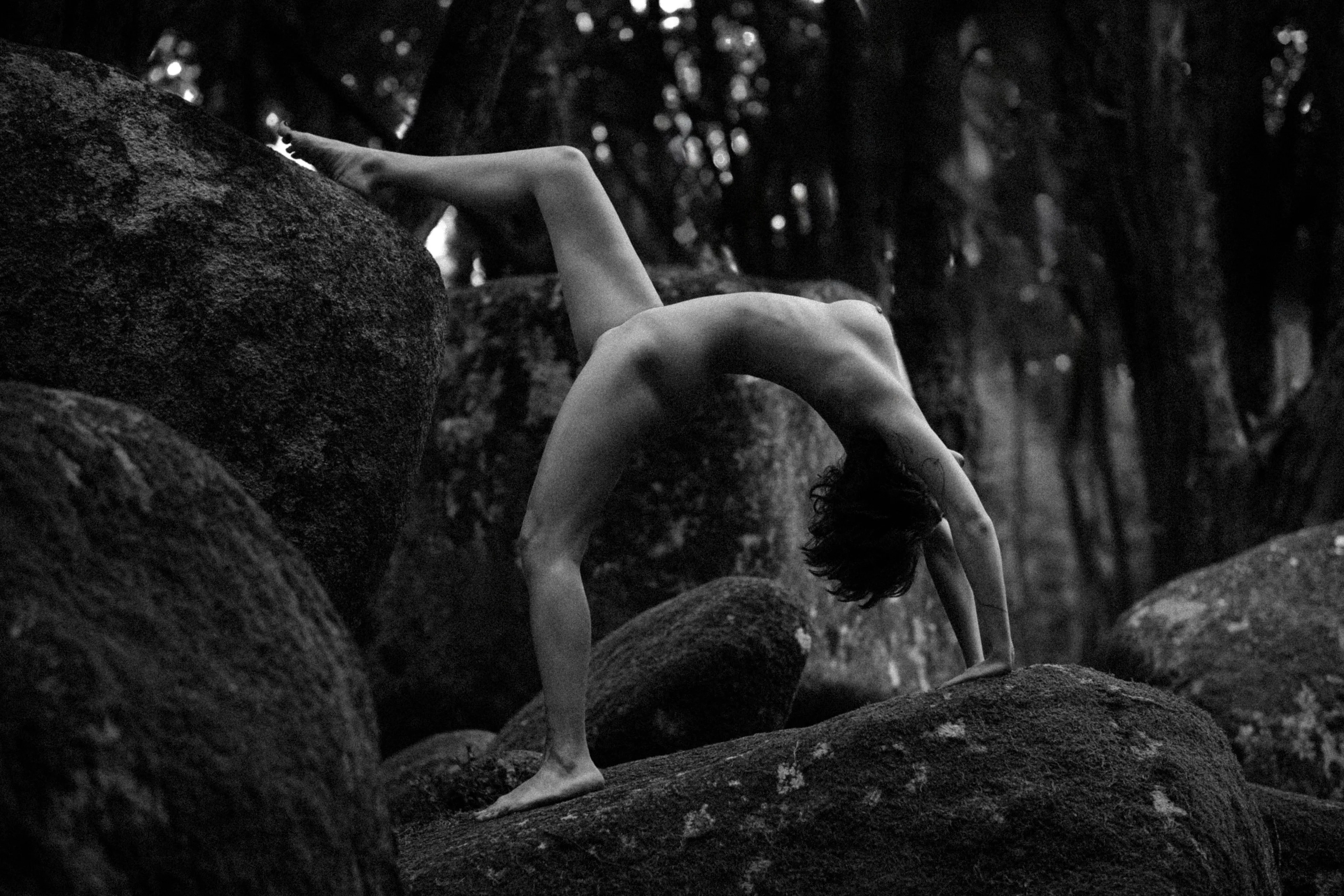 Her body bends like the branches, an arc of grace in the wild landscape.