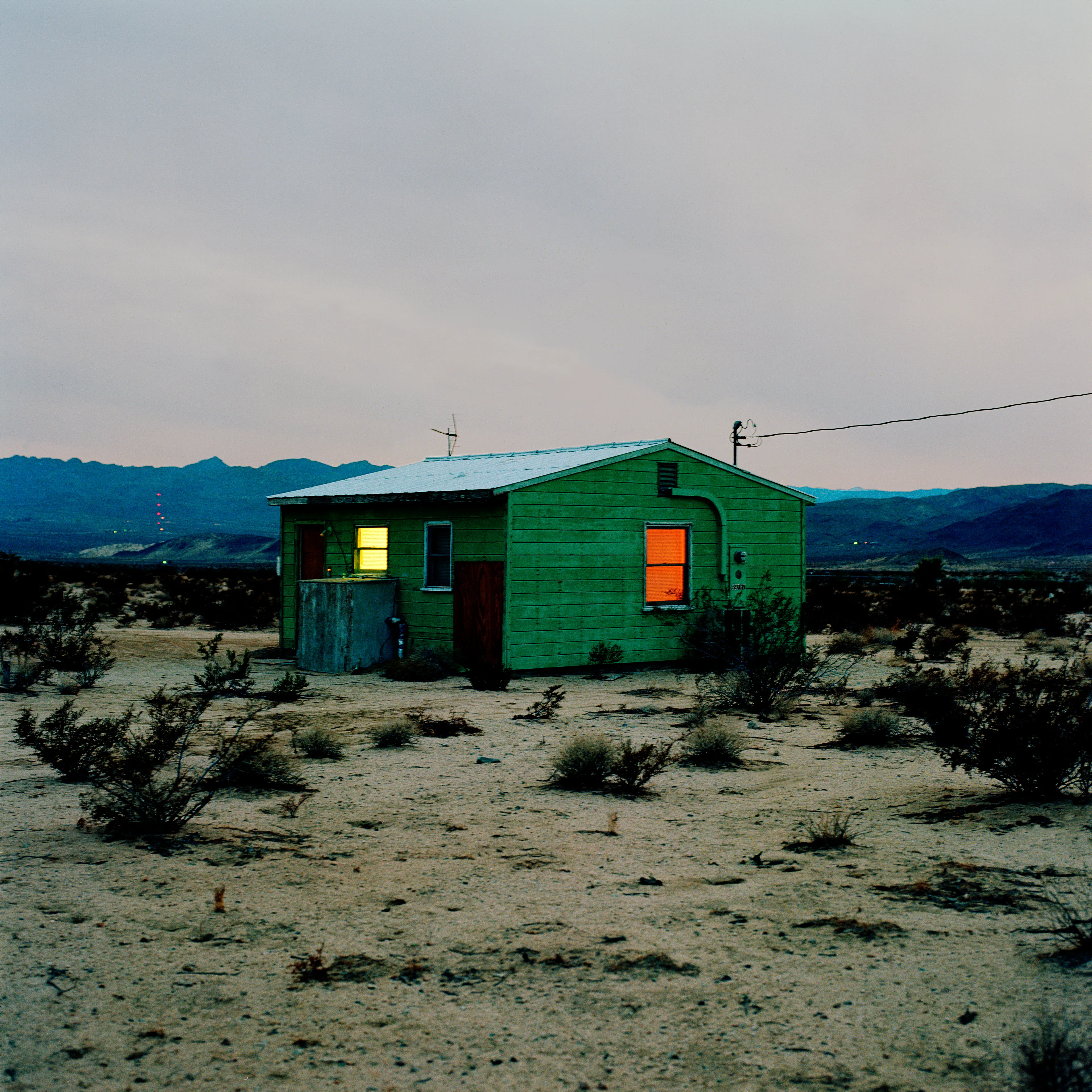 “These are photographs of isolated structures in the high desert of Southern California. All of the images are made in the east end of the Morongo Valley Basin, Wonder Valley, and the area surrounding the town of Twenty-Nine Palms. This is an area approximately one hundred- and fifty-miles due East of Los Angeles. From the oceans edge in L.A., to the area that I am photographing, the landscape is continuously occupied. This area is the final edge of a vast urban expanse. For social, financial, or personal reasons individuals are pushed, or pulled, or simply seek this literal cultural edge. Beyond this point is unoccupied desert.  In the past I have perused projects which dealt with the iconography of transcendence and the sublime. In other projects I have investigated the literal desire to get "outside" of or beyond the cultural (a desire with the ironic consequence of transforming the natural into the very condition one wishes to escape). It is this conceptual trajectory which has led me to this current body of work. This current body of work is an extension of the investigation begun in the "four landscape" portfolio. The structural rigor of that work has been replaced with concerns which are aesthetic and social. On the simplest level I am drawn to the vernacular character of the architecture (painted with a Home Depot palette) as well as the amazing visual character of these structures on this vast desert plain lit by an extraordinary light. However, at base, my primary interest is to create images which are iconographic of a desire. A desire to be "beyond", a desire to be alone, a sign of man on the landscape”. - John Divola.

Edition: 1 of 1