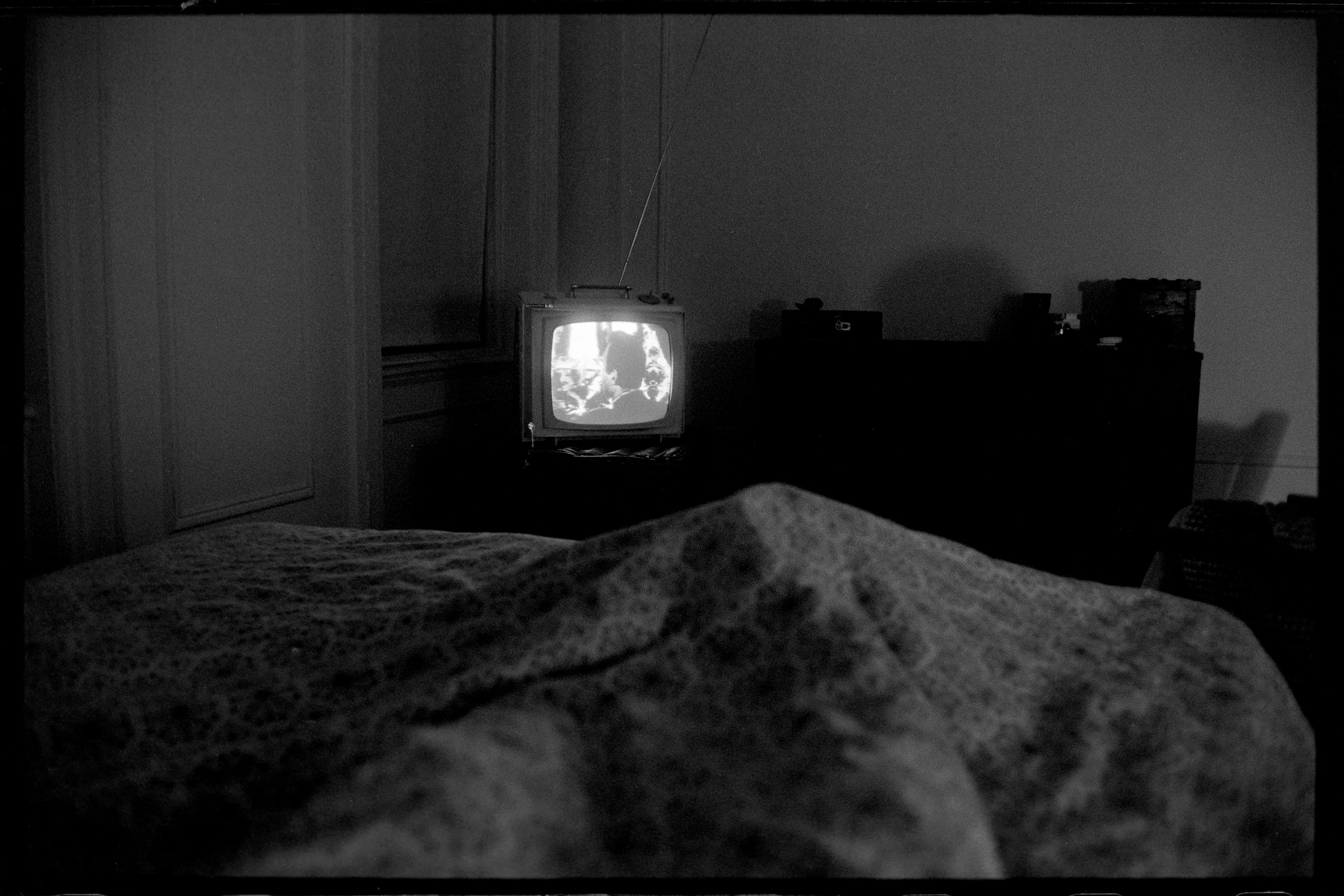 New York City, USA, 1966

In this New York City bedroom, 1966, there sits a solitary television set, a recurring motif that echoes the composition found in Sequels #5. The television, a symbol of technological progress and a medium for cultural transmission, holds a profound significance in this photograph.

This was a time when television was undergoing a transformative evolution, moving from the simplicity of black-and-white to the complexity of color. The change was more than just technological; it was a reflection of the sociocultural shifts and significant events of the era, all of which found their way into the programming aired on this small screen. Thus, the television set is not just an object; it is a window into the period it represents.

The photograph, therefore, presents an intriguing duality—an image within an image. The physical television set, the centerpiece of the image, is contrasted with the transformative content it displays. This juxtaposition, an embodiment of the broader cultural shifts occurring in society during this period, lends a rich complexity to the photograph.

In the tradition of our ongoing inquiry into the language of photography, we can view this image as a testament to its time. It's not merely the depiction of a television set within a bedroom, but rather a capsule of a moment in history, preserved within the four corners of a photographic frame. The photograph speaks to the evolving role of television as a nexus of technology and culture, an agent of change, and a mirror reflecting the world outside the viewer's window.