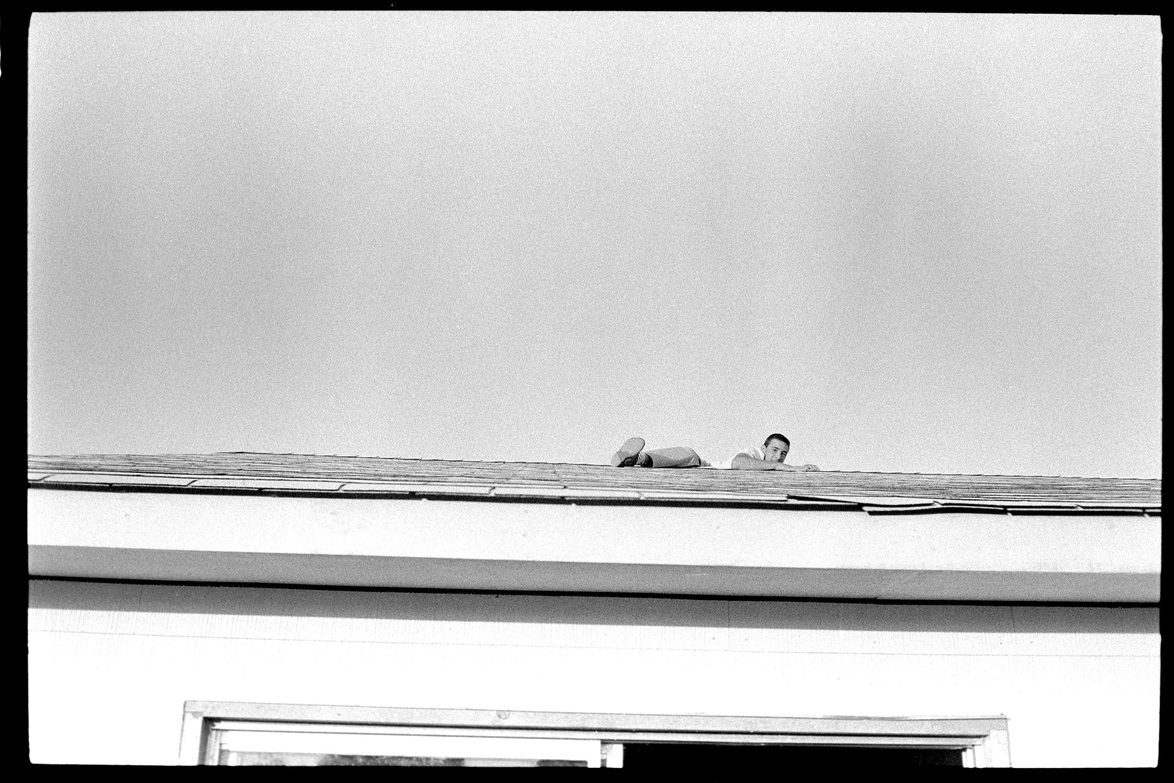 New York City, USA, 1965

A picture of the roof of a house in New York City where we see the foot, arm, and head of a man climbing over the edge.