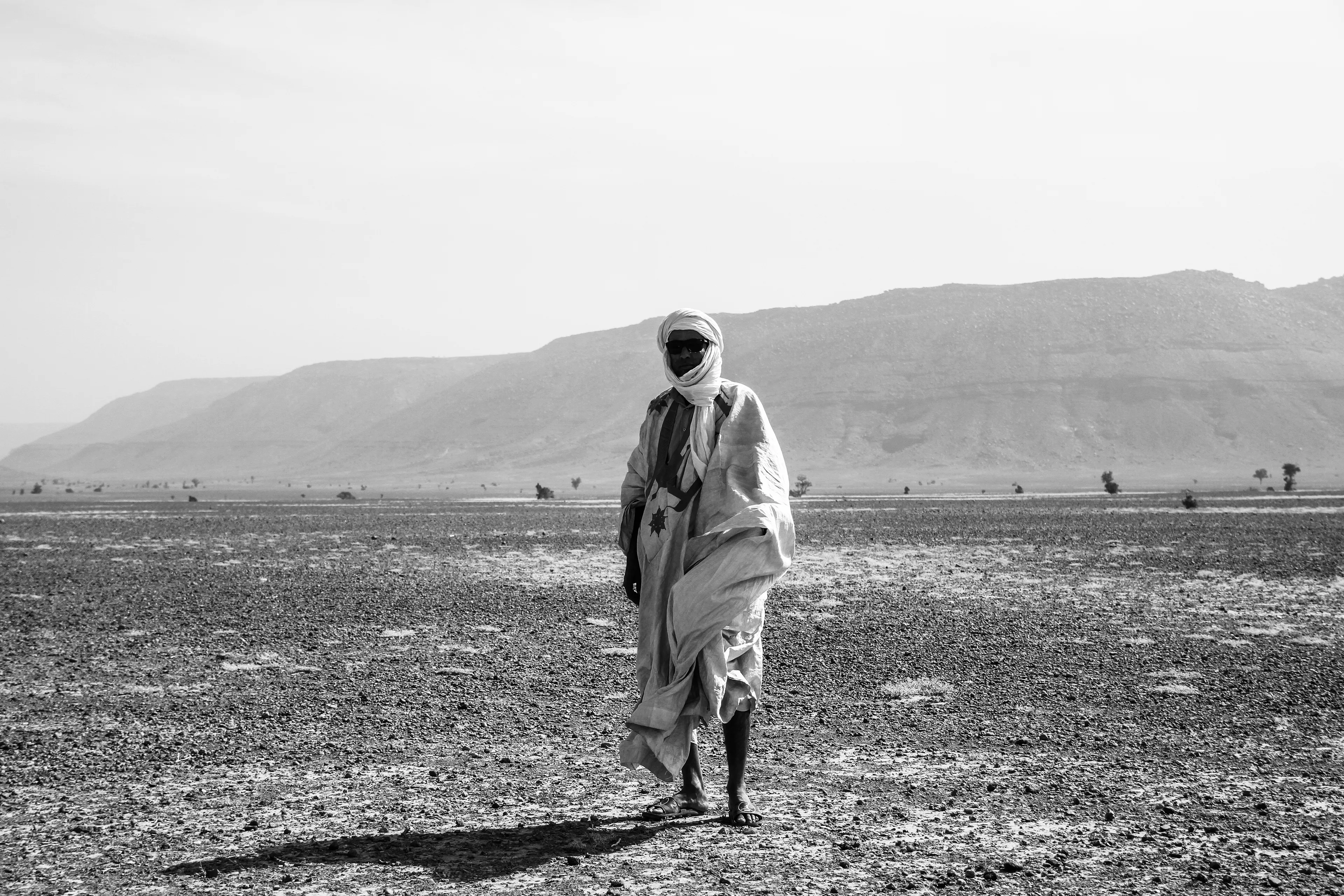 Amidst the endless sands, rocky formations rise, breaking the monotony of the desert and standing as silent witnesses to time and the harsh landscape around them.
