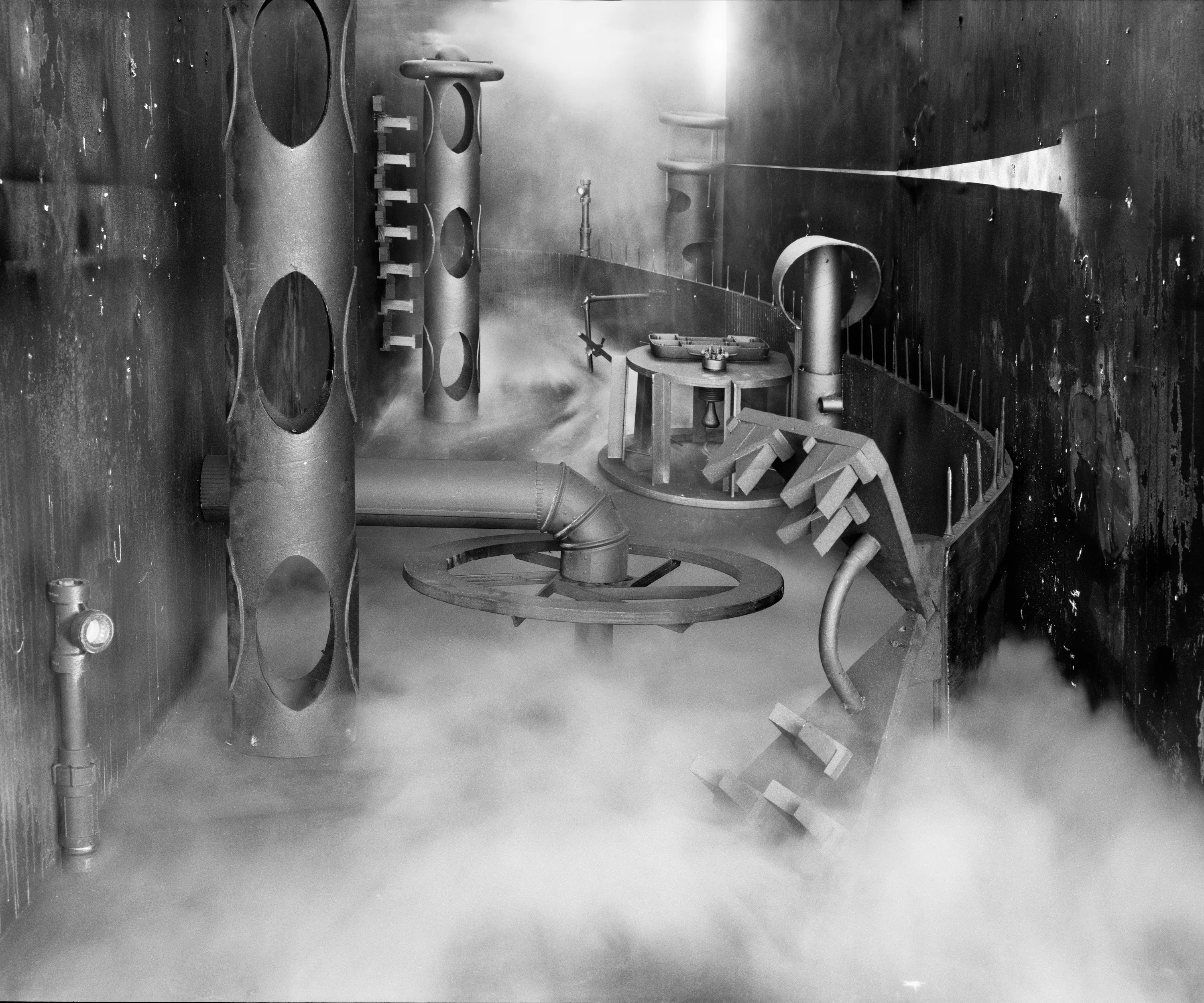 In conjunction with the exhibition in our physical gallery, Assembly presents “Afterwork” by Rodrigo Valenzuela. Based on the ghostly absence of workers in an indeterminate time and place, this work is at once futuristic and harking back to a century ago.

In staged sets suggesting abandoned factories, Valenzuela wishfully foments a revolution, enabling workers powerless in the face of relentless international movement of capital to flee or perhaps overrun their workplaces. As in a science-fiction universe where we feel a potential reality just out of reach of our present, Valenzuela’s scenes meld mechanical objects with steam or smoke, suggestive of steel manufacturing, a cloud of sweat-the only bodily proof of human toil-or a cinematic trope of futuristic atmosphere. In these eerily depopulated scenes, viewers are prompted to envision alternative possibilities to histories of workers dispossessed, or made obsolete, and industries that thrived on human pain.

Rodrigo Valenzuela is a Chilean-born, Los Angeles-based artist working in photography, video, painting, and installation. Not satisfied with the existing romanticism of blight and resurrection, Valenzuela opts for image making that is defiantly labor intensive and ambitious in scope. Detritus and industrial parts are scavenged over time, taken apart or reassembled, and transformed in the artist's own studio backdrops, then turned into flat images that confuse the viewer with scale shifts and multiple references. Using autobiographical threads to inform larger universal fields of experience, his work constructs narratives, scenes, and stories that point to the tensions found between the individual and communities. Much of his work deals with the experience of undocumented immigrants and laborers. His work has been exhibited internationally, including solo exhibitions at Lisa Kandlhofer Galerie, Vienna; the Ulrich Museum of Art, Wichita, KS; the Art Museum of the University of Memphis, TN; Klowdenmann Gallery, Los Angeles; the Frye Art Museum, Seattle; and Museo de Arte Contemporaneo, Santiago, Chile. In 2021, Valenuzlea was awarded a Guggenheim Fellowship in Photography and Smithsonian Artist Research Fellowship.