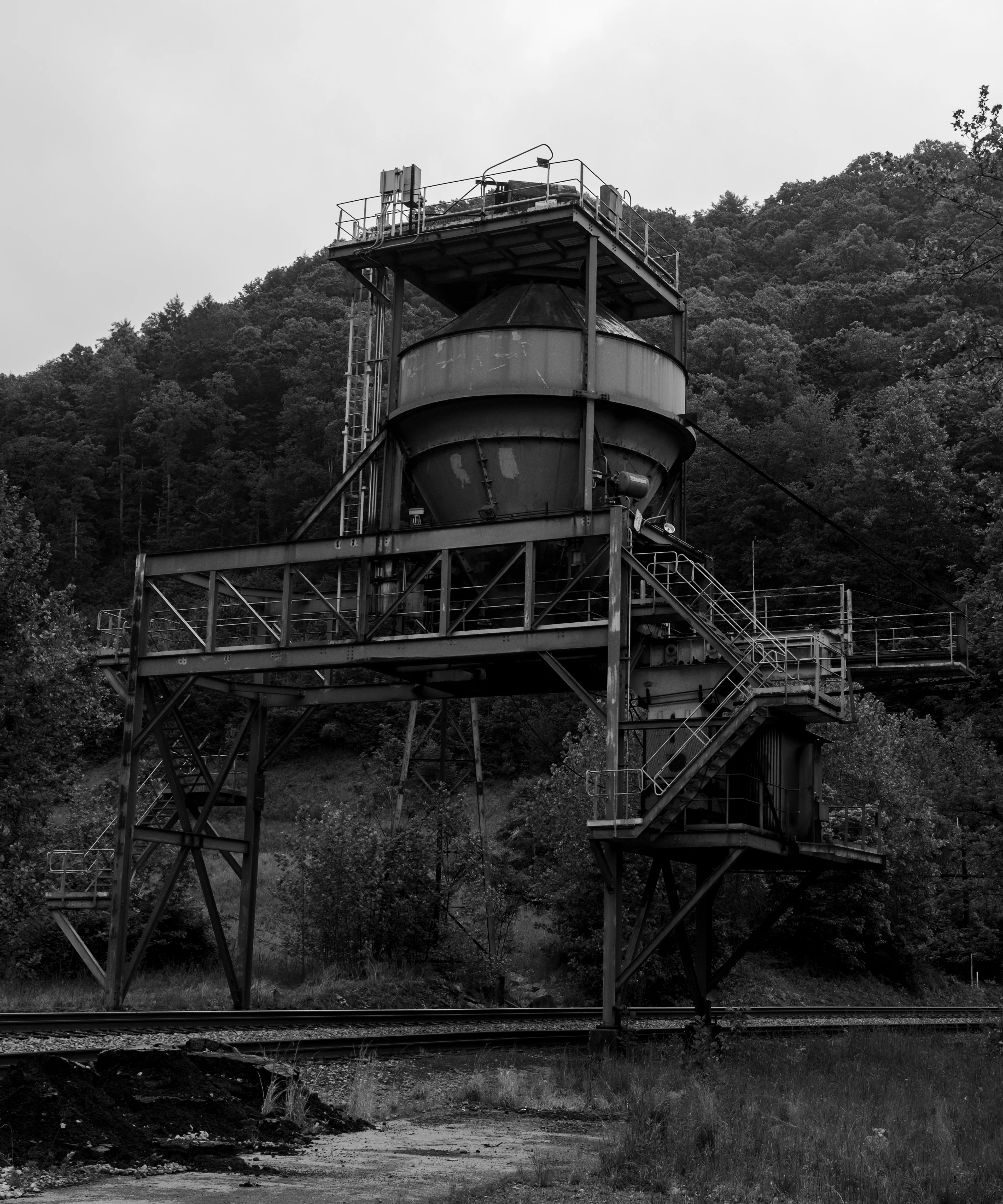 West Virginia and the Appalachian Mountains have an allure about them that is almost impossible to ignore. The country is rugged and so are the individuals who inhabit these mountains. As you ascend into the deep mountain of Appalachia, the roads begin to wind almost unimaginably. As you drive, sharp left and right turns seem to never end as Empress trees and Black Pines hug the roads like guardians of a passageway. Large metal structures from coal mines stand like old ruins. As you continue to drive deeper and deeper within the mountains small towns start to pop up, not more than 1/2 mile in length alongside Route 16. For every ten homes there seems to be a church, affirming that the presence of religion is strong and deeply rooted in these mountains. 

A small church by the name "The House of The Lord Jesus" sits on the side of the road in the quiet and humble town of Squire, with a population of fewer than 300 people. If you didn't know any better, you'd think it's just like all the other churches you pass by while driving up the windy mountain roads. This Holiness church practices what is called "signs following." The church is small and is run by pastor Chris Wolford. Twelve church pews (six on each side) take up the majority of the space. Old wood panels cover the walls and red burgundy carpet melds with a wood floor at the front of the church. As you walk down the center of the church you see women laying on their knees bent over the pews praying and crying before the service begins. The sound of rattlesnake rattlers fill the air and multiple boxes are laid out behind the pulpit, while the guitar begins to blair over the speakers at full volume. The music is incredible...with a mix of delta blues and bluegrass, it's a style of its own and specific to this type of worship within the applications. Women are spinning in their flowing dresses and their long hair is wrapped up in cloths. Chris grabs a mason jar. Within it is a mixture of water and strychnine poison. Small dixie cups line the front of the pulpit as he fills one and takes a shot. A bottle is brought out, stuffed with alcohol and homemade wick. He lights the top and flames rise above the glass bottle. He screams passionately in praises as he holds the bottle underneath his chin. He eventually passes the lit bottle to his mother as she also holds it under her chin and begins to spin in circles. Chris jumps and dances in a stomping manner and praises the Lord as beads of sweat and tears stream down his head and face. He reaches and grabs one of the wooden boxes from behind him, and flips open the plexiglass lid. He pulls out a diamondback rattlesnake and holds it straight into the air. He jumps around, dances, and screams in praise as the serpent rests in his hand and looks over the church. The energy is so palpable it makes the hair on the back of your neck stand up and the feeling is almost unexplainable.

There is death in this, as well as a lot of suffering for the church and this whole region of West Virginia. But I came to understand why the Appalachians have this mystic quality. They're full of love and compassion...you just have to sift through all the coal dust to find it.

Welcome to GLORYLAND.

A grant provided by Fellowship Futures supported this image and the minting of the GLORYLAND collection.